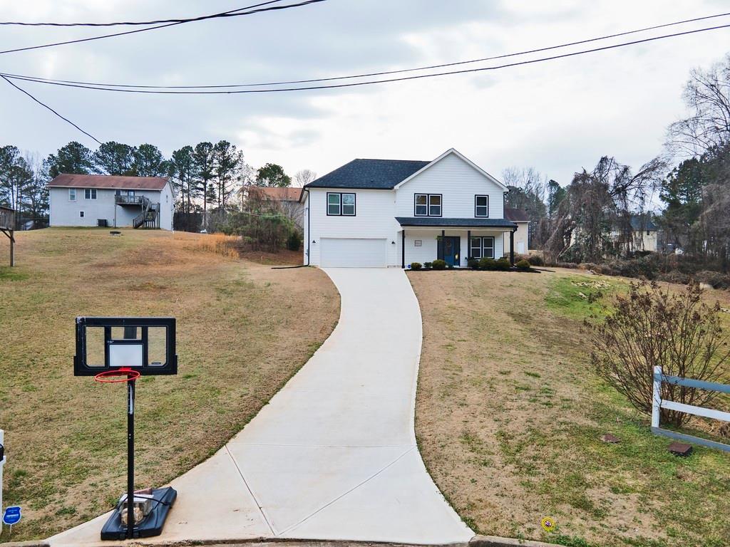 View of front facade with a front lawn, an attached garage, concrete driveway, and a porch