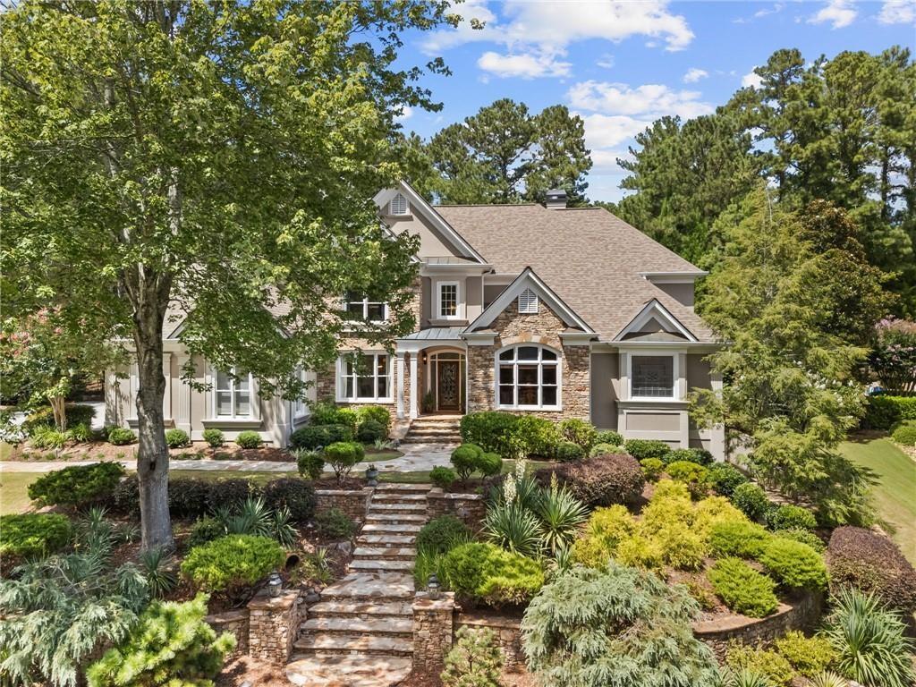 Nestled within an exclusive gated community, this executive residence offers timeless elegance and modern comfort on one of the most sought-after lots in the neighborhood. Perfectly positioned along the 11th fairway of the Golf Club of Georgia, the home boasts a private, fenced, flat backyard with lush lawn, soothing water features, and a covered patio designed for year-round enjoyment. Inside, the primary suite on the main level provides a serene retreat with walkout access to the backyard oasis. The heart of the home is an eat-in kitchen with views to both the dramatic two-story great room and the inviting keeping room, creating a seamless flow for daily living. Entertain with ease in the formal dining room, complete with a butler’s pantry and wet bar or retreat to the richly appointed library/office for quite productivity. The second level is thoughtfully designed with three spacious bedrooms, each featuring its own en-suite bath. A study nook or secondary office space offers flexibility for focused work or study time. The terrace level extends the lifestyle experience with multiple recreation and entertaining spaces, a private guest suite with dedicated bath, a fitness area, and generous storage. Located within Alpharetta’s Windward community, don’t miss all the amazing amenities that Windward offers such as lake recreation, play grounds, dog park, community garden and so much more. Enjoy top rated north Fulton schools and ease of access to GA400, downtown Alpharetta and Avalon. Blending sophistication and comfort, the home is as functional as it is elegant-ideal for both grand entertaining and intimate family living.