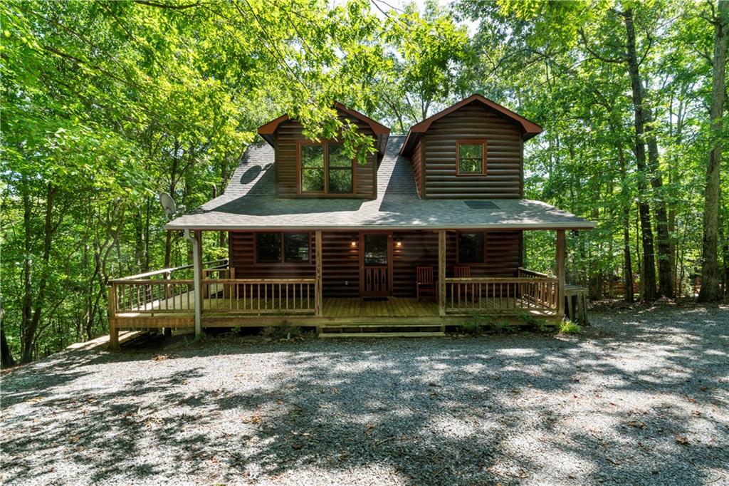Escape to your private mountain sanctuary in the coveted My Mountain community! With the convenience of all-paved roads, you're just a scenic 10-minute drive from the vibrant shops and dining of downtown Blue Ridge. This immaculate, move-in ready log cabin is a rare find, perfect as a peaceful retirement haven, a multi-generational family retreat, or a high-demand short-term rental investment. Step inside and be greeted by the warmth of a spacious great room, where a crackling wood-burning fireplace invites you to unwind. The open-concept layout flows seamlessly into a modern kitchen, fully updated with brand-new stainless steel appliances. The main level also features a convenient primary bedroom with a full ensuite bathroom, complete with dual 'his & her' sinks. Ascend to the upper level to discover a second private bedroom suite, also boasting a full ensuite bath and double vanities, offering a perfect retreat for family or guests. The fully-finished terrace level is a game-changer, featuring a complete in-law suite ideal for extended stays or as a separate rental unit. This versatile space includes a cozy living area with a gas log fireplace, a brand-new kitchenette, a sleeping area, and a full bath. Your outdoor oasis awaits! Entertain and relax on the brand-new, two-story deck, perfect for grilling while overlooking your private, wooded lot. Spend your evenings sharing stories around the newly built stone fire pit or soaking in the hot tub on the peaceful, screened-in porch-a true year-round luxury. With recent major upgrades, an ideal location, and a floor plan built for comfort and income, this is the Blue Ridge opportunity you've been waiting for. Don't let this dream slip away. Schedule your private showing today and start living the mountain life!
