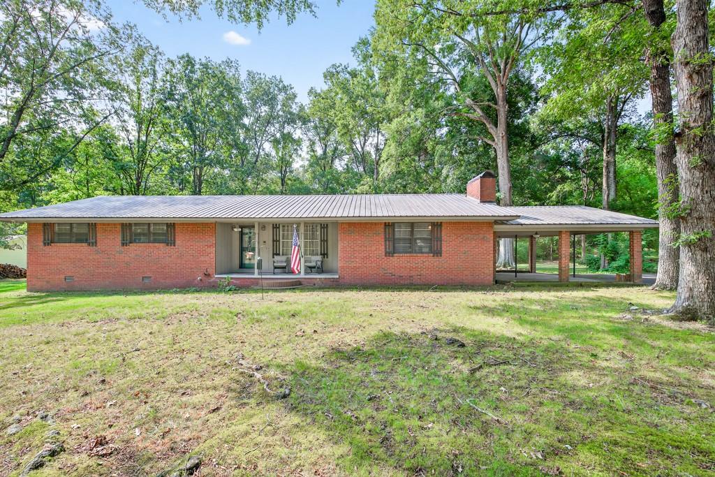 Set on nearly an acre (.94 acres across 2 lots) in an established neighborhood, this classic 4-sided brick ranch with a metal roof blends timeless character with thoughtful updates.
Step inside from the 2-car carport, where a wood door accented with stained glass opens to the inviting interior. The spacious great room is anchored by a wood-burning fireplace with tiled ceilings and a small workshop.
A separate front living room, filled with natural light, features an open concept living area and adds to the home’s warm, welcoming feel.
The kitchen has been beautifully remodeled and offers abundant cabinetry, a 4-burner gas range/oven. The adjacent laundry space adds everyday convenience.
The large primary suite includes a luxurious private bath with a tile shower, while the secondary bedrooms share a hall bath with a touch of modern flair.
At the back of the home, the sunroom (not counted in the square footage) provides a peaceful retreat with views of the level, fenced backyard, shaded by mature trees. A storage building with two lean-to shelters offers plenty of space for tools, hobbies, or outdoor equipment.
Recent upgrades ensure peace of mind, including:
Partial New Flooring
New HVAC (12/2023)
Freshly remodeled kitchen
Septic cleaned, re-piped, and upgraded (2023–2024)
Updated plumbing and electrical
Three trees removed + limb trimming
New backyard fencing
With its generous parking area, this home is perfect for gatherings. All this comes with the convenience of being close to downtown Calhoun, schools, shopping, dining, and I-75 — and with no HOA fees.