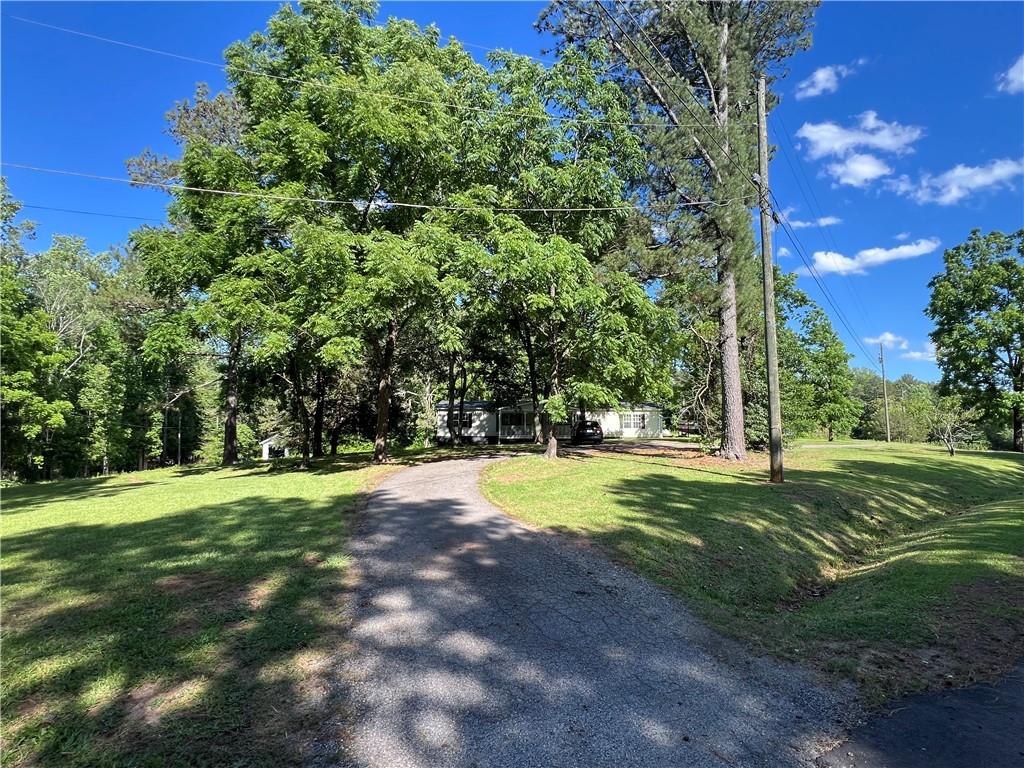 Exceptional opportunity for building your dream home(s) on a gorgeous piece of SERENITY in East Forsyth, minutes from Lake Lanier! Highly desirable area. With Fourmile Creek winding through the back section of this property and A1 zoning, this parcel offers the flexibility to develop a private estate, mini compound, or multiple homesites. Property is already equipped with a total of three building sites on these two tracts, complete with existing electric, power, water and septic connections. The groundwork is set for immediate expansion. The existing mobile home provides a place to live or rent while you build. EASY instant rental income and has a brand new roof! Nestled on a quiet, secluded road—yet you’re just minutes from Lake Lanier’s beaches, top-rated schools, parks, and all the amenities of Cumming plus easy commute to Gainesville and Dawsonville. Whether you’re envisioning custom homes, your dream estate, or a small farmstead, this property checks all the boxes: location, infrastructure, and development potential. Opportunity to purchase addl 6 acres in the very back for a total of 10.68 acres. Appointment is required. Both shipping Containers on 2nd site to be removed prior to closing. The shed(s) will remain. Property and home sold AS-IS.