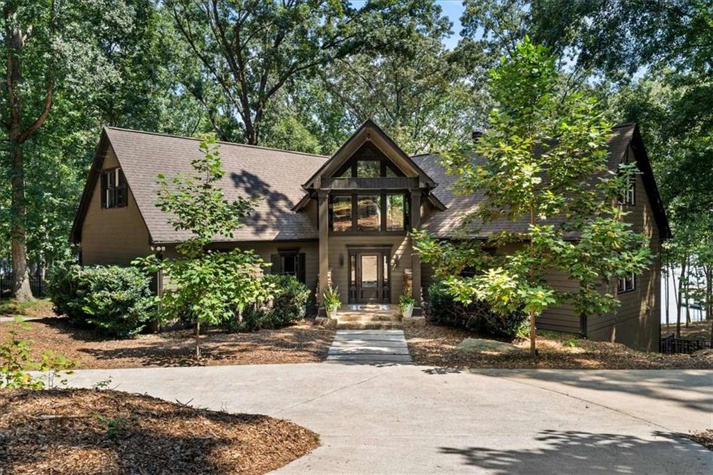 This stately yet charming 7-bedroom, 6-bathroom Lake Lanier estate with 7,025 sq ft sitting on more than 800 feet of shoreline, offering wide, deep-water views and direct access to the lake is sure to steal your heart. A classic ivy covered gate welcomes you in to the 1.33 acre property. The gentle backyard path to the lake leads to a 32x32 double-slip party dock with electricity, designed for easy days on the water. Situated in deep water and a coveted, quiet, no-wake cove with easy access to big water. Remodeled in 2017, the home was thoughtfully updated by the owner/architect to add space, comfort, and style on every floor. While conveniently located in Flowery Branch, the property backs onto over 20 acres of Corps land, creating an enjoyable private setting and a natural refuge for local wildlife-without the added upkeep or property taxes; complete with your own private beach. Inside, the home offers three primary suites, four secondary bedrooms, and two full kitchens, giving you flexibility for multigenerational living, hosting loved ones, rental opportunities, and full-time lake life. Natural light pours in from every floor-to-ceiling sliding glass window in the living and dining area, framing idyllic views of the cove, wooded land, and deer passing through. Features include oak hardwood floors, spa-quality showers with custom tile and stonework, all in a soothing palette. Nature provides plenty of light during the day and dimmable recessed lighting throughout the home illuminates the impressive architectural features in the evening. The lower level, with durable stained concrete floors, is well-suited for a game room, workshop, or garage and includes abundant storage for lake gear and supplies. An attached .75-acre lot adds even more opportunity. Already perc-tested for a 5-bedroom home and with a dock permit in hand for another 32x32 double-slip dock, it's ready for a guest house, rental property, pool, or multi-bay garage. 6680 Woodlake Drive is a rare combination of privacy, convenience, and prime lake access-an inviting place to gather, recharge, and enjoy the best of Lake Lanier.