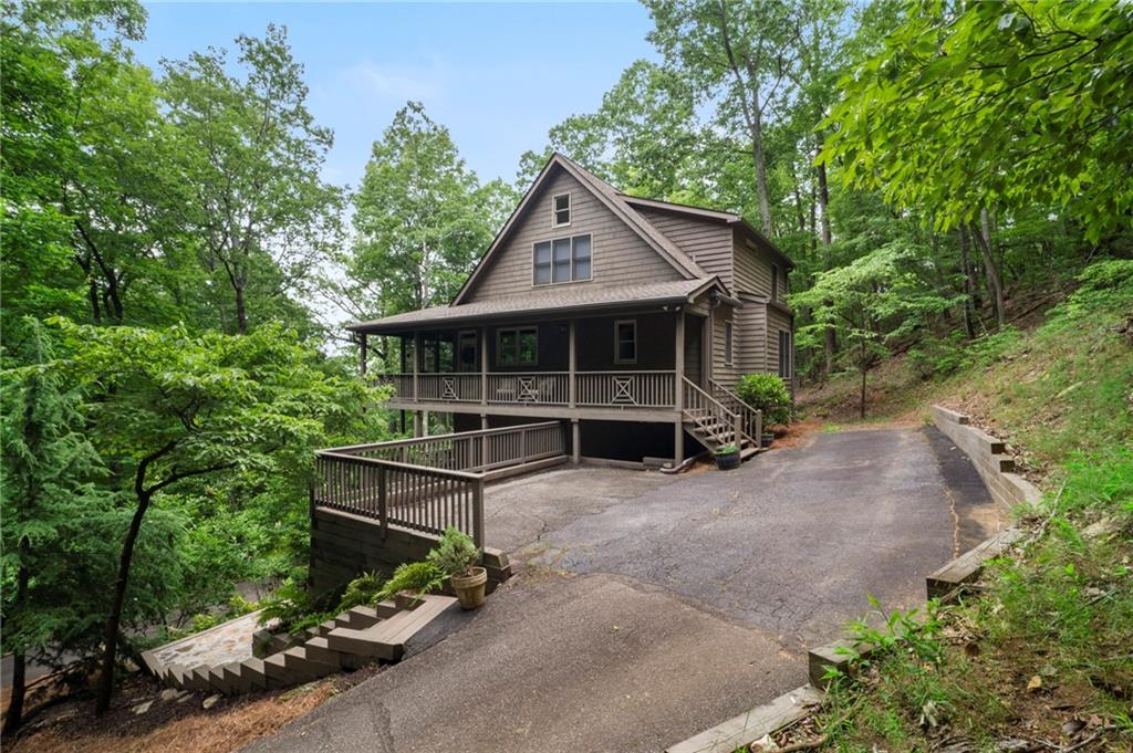 Nestled at the end of a quiet cul-de-sac in the sought-after gated community of Big Canoe, this beautifully updated Southern Living-style chalet offers the perfect blend of mountain charm and modern comfort. Located at the foothills of the North Georgia Mountains—just an hour from Atlanta—this home provides resort-style amenities in a private, natural setting. Upgrades include newer roof, newer HVAC, newer hot water heater, a whole-house dehumidifier, all-new lighting, plumbing fixtures, and hardware.
From the moment you arrive, you’re welcomed by a gracious front porch that wraps around for a perfect place for relaxing or entertaining. Step inside to discover a spacious, light-filled great room featuring cathedral wood paneled ceiling, a stacked-stone fireplace, and triple set of French doors that open to a large screened-in porch, seamlessly blending indoor and outdoor living. The porch has a full sized dining table, a seating are, three overhead fans to keep it cool in the Summer, and carnival lights to add a festive touch.
The main level boasts an open-concept design with a beautifully renovated kitchen that includes quartz countertops, a stylish backsplash, a large island with ample storage, a butler’s pantry with brick flooring, and a premium KitchenAid appliance package. The spacious dining area and great room flow effortlessly, creating an ideal gathering space.
The primary suite on the main level features a walk-in closet and a custom shower. Upstairs, you’ll find a private guest suite with a full bath, a second guest room with adjoining bath, and a versatile loft area perfect for a home office. The terrace level can be accessed from the main level or from its own entrance off the full-length lower deck and offers another bedroom, a large family room for entertainment, laundry room, and abundant storage. There are two driveways and parking pads for plenty of parking.
This mountain chalet is perfect for full-time living or a weekend retreat. There are cameras in the home on both levels. Buyer to verify all information and dimensions deemed important.