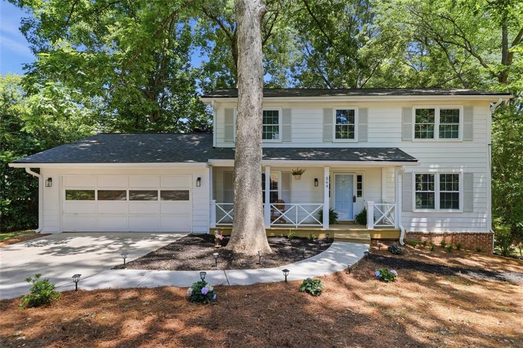 View of front facade featuring covered porch, an attached garage, and concrete driveway