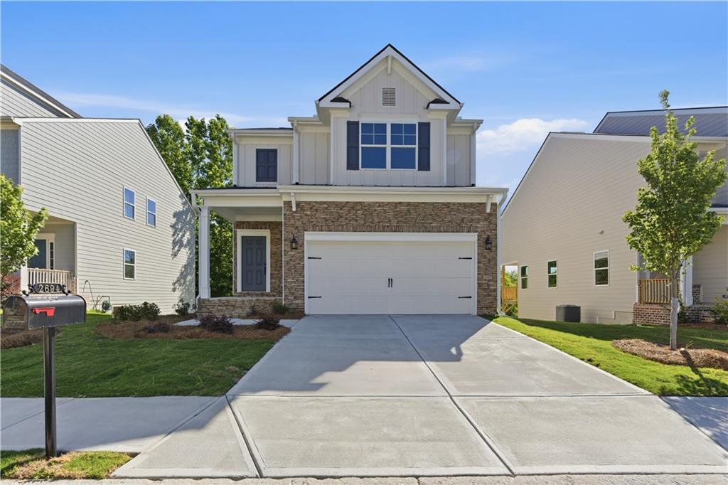 View of front of property with a garage, a front yard, a shingled roof, and driveway