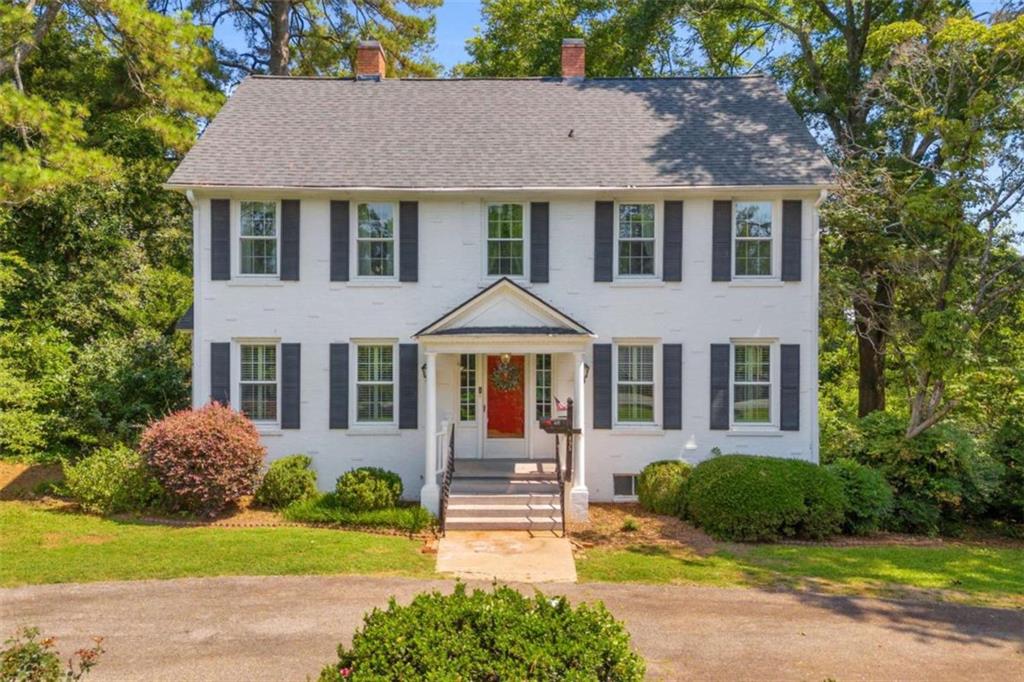 Timeless style and modern convenience come together in this beautifully maintained Colonial Revival home on a scenic 0.919-acre lot, just minutes from downtown Commerce. With 4 spacious bedrooms and 3 full baths, this classic two-story home offers two primary suites: one on the main level and another upstairs, providing flexibility for multi-generational living or guests. The stately exterior features painted white brick, black shutters, and a welcoming front porch that opens into a bright and inviting interior. You'll love the spacious layout, charming architectural details, and natural light throughout. A detached 2-car metal garage sits just behind the home, perfect for parking, storage, or hobbies. Surrounded by mature trees and lush landscaping, this property offers privacy, curb appeal, and convenient access to shopping, dining, and schools in Commerce. This is a rare opportunity to own a true Southern classic with room to grow and enjoy.