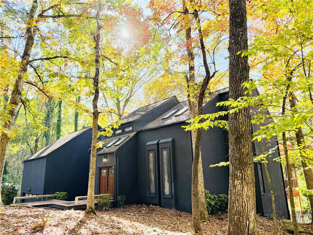 View of side of home with stucco siding and roof with shingles