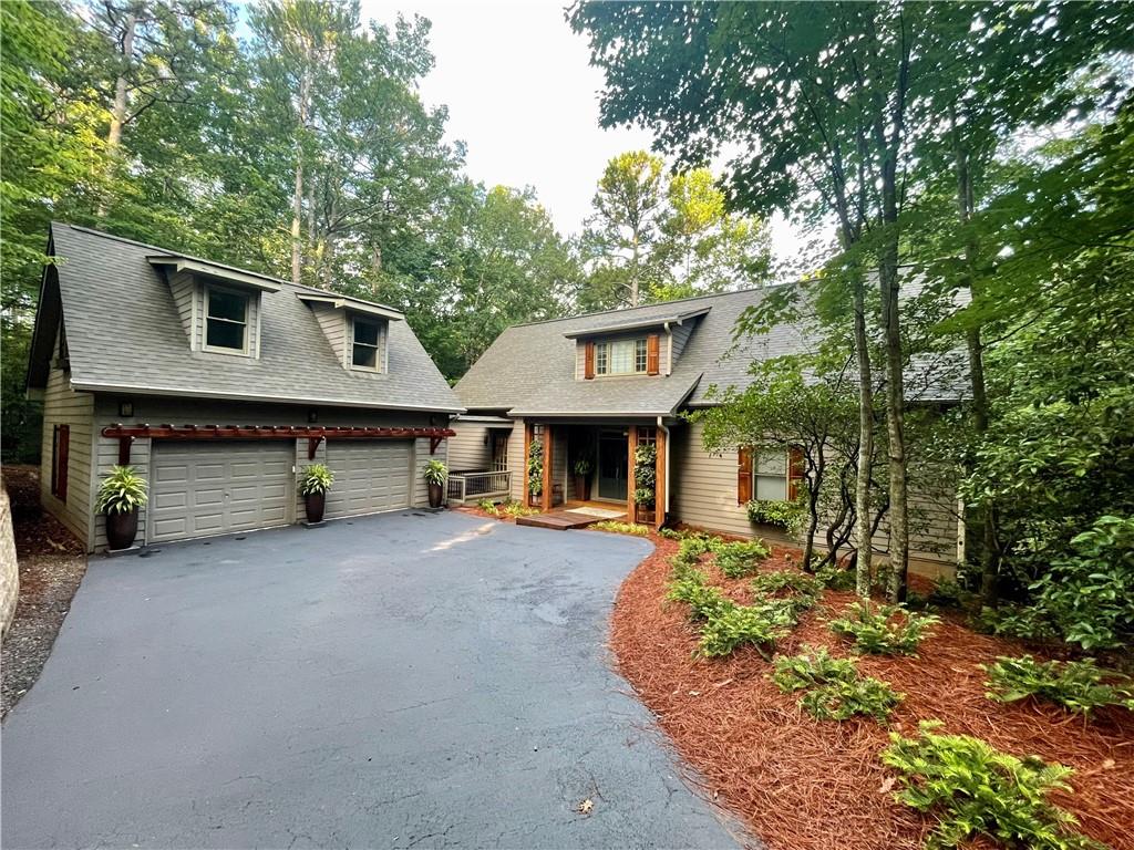 EXCEPTIONAL LOCATION just a short walk to the Lake Petit trail behind the home. You’ll especially love the sound of the creek and gentle waterfalls from your back deck!!! From the moment you arrive, the curb appeal is unforgettable-so much so that this home was featured on a PBS program highlighting beautiful home finishes. Step inside to a welcoming entryway that opens to a dramatic wall of windows, giving the sensation of living in a treehouse. Rare acacia hardwood floors and an open-concept kitchen create an effortless flow for entertaining and everyday living. The kitchen, filled with natural light, boasts a generous center island-perfect for casual dining or serving a stunning buffet. Just beyond, the deck overlooks a lush forest, with direct access to a trail that leads to cascading creek rapids and a hidden cove on Lake Petit. The owner's suite features its own wall of windows, a spacious walk-in closet, and feels like a serene ensuite retreat. Upstairs, two private bedrooms and a versatile loft-ideal for a library or home office-offer comfort and flexibility. The terrace level provides a spacious family room for gatherings, plus a private bedroom with ensuite, making it easy to host guests or multiple families. Step outside to discover your hydrangea garden, protected by deer fencing, just beyond double doors that invite the outdoors in. This is more than a home-it's a lifestyle. Designed from a Southern Living house plan, it has been showcased not only on PBS but the butterfly garden on the back deck was also featured in Southern Living magazine. You simply must see this extraordinary property in person!