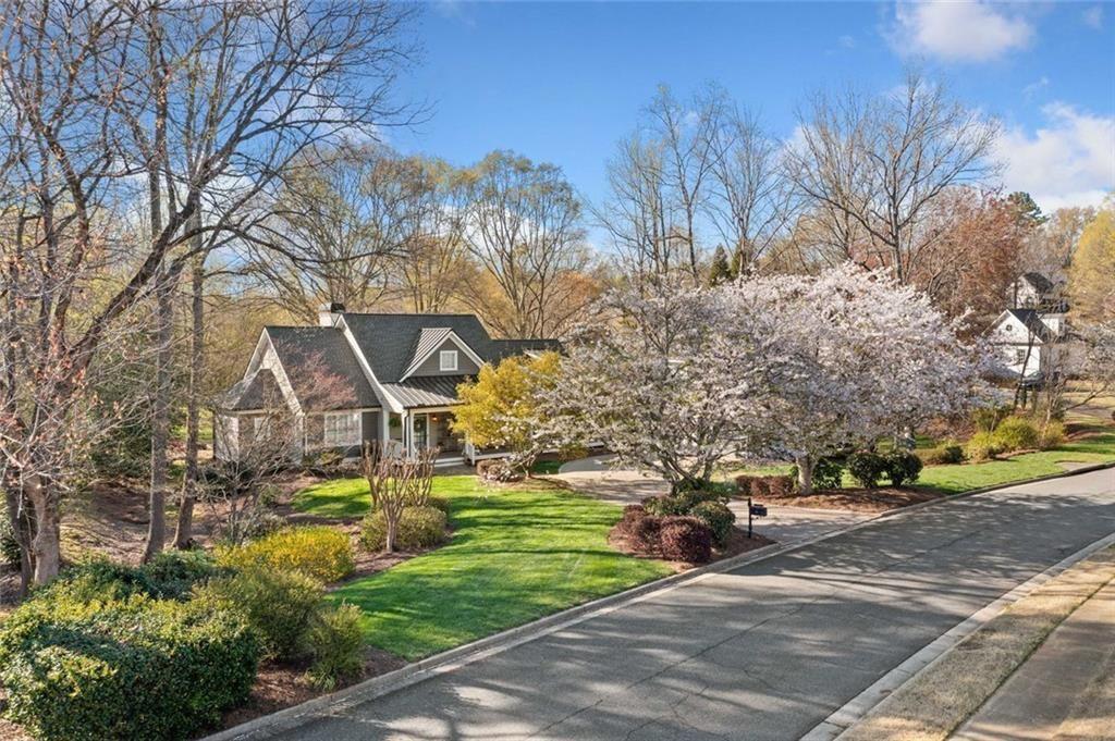 This move-in ready Ranch in Bradshaw Farm brings together updated interiors, a full in-law suite, nearly an acre of land bordered by two creeks providing unmatched privacy, and a location that puts golf, pools, tennis, and more just a short walk or cart ride away. With a newer roof, new HVAC, 2 water heaters, tankless and a brand new 50 gallon water heater, whole-house water filtration system, and even a FEMA-approved storm shelter, it’s a rare mix of charm, function, and peace of mind.
Step through the front porch into a bright, open floor plan with refinished hardwoods and updated lighting throughout. The main living space features a vaulted ceiling, built-ins, and a gas fireplace framed by a classic wood mantel. The fully renovated kitchen includes quartz countertops, shaker cabinetry, stainless steel appliances, and a custom farmhouse sink, flowing into a wet bar with natural light all around. Just off the kitchen, the screened porch and large back deck invite you to relax and listen to the creeks running along both sides of the property.
The primary suite is privately situated and features a spa-inspired bathroom with a freestanding soaking tub, marble tile shower, and dual closets—one of which serves as a reinforced storm shelter. Private office or flex room just off primary suite. Two additional bedrooms and renovated Jack and Jill bath with an additional freestanding tub and separate shower featuring handmade Spanish tile complete the main level, offering flexibility for guests or workspace.
Over the oversized detached garage, a full in-law suite adds a fourth bedroom or living area, kitchen, and bath with a separate entrance—ideal for visitors or extended stays.
Outdoors, the flat, landscaped yard offers space to play, garden, or entertain. In Bradshaw Farm, you’ll also enjoy access to golf, multiple pools, tennis courts, pickleball, volleyball, basketball, a clubhouse, and playground—all in one of Woodstock’s most sought-after neighborhoods.