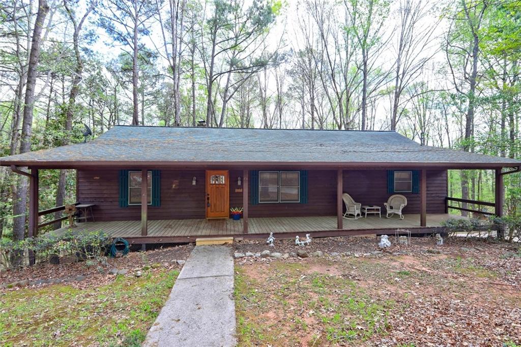 Tucked away on a serene, wooded lot, this move-in-ready, charming home welcomes you with a full-length covered front porch, perfect for relaxing. Inside, the spacious great room boasts a beamed ceiling, a floor-to-ceiling stone fireplace, and a high-efficiency pellet stove, perfect for cozy winters. The driveway leads you through the trees of this 3.5+ acre lot to the home. It's perfect for your morning coffee or sitting in your rocking chair on a rainy day. The fireplace features a pellet stove, capable of heating the entire house and reducing your electric bill in the winter. There is also a furnace if you prefer, and the fireplace can be converted back to a wood-burning fireplace. Walk out onto the spacious back deck from the great room, and you are surrounded by nature. The kitchen offers ample cabinetry, counter space, and a breakfast bar. The owner's suite boasts a walk-in closet, en-suite bath, and French doors to the back deck, two additional bedrooms, and a full bath complete the main level. A large unfinished basement room offers endless possibilities. The oversized garage accommodates three large vehicles, and a covered carport can accommodate an RV or boat. The house is connected to public water, but there is also a well that is convenient for washing vehicles, or for irrigation, pressure washing, etc. There are spigots for accessing that water on the well house and by the turnout in the driveway. Enjoy privacy, space, and nature. Schedule your showing today!