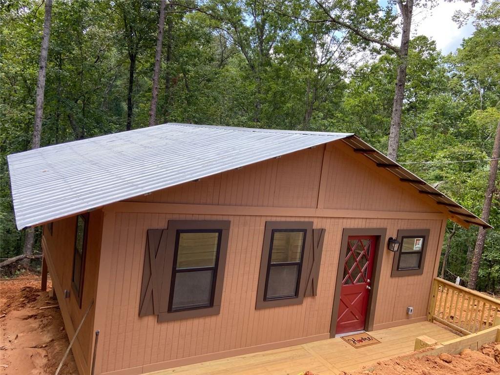 HURRY AND GRAB THIS EXCLUSIVE, SECLUDED CABIN HIDEAWAY in one of the best-kept-secrets in an older but 'up and coming' trendy LAKE HARTWELL community in Toccoa! This 'rustic reno', 2bd/1ba. compact country cabin w/resurfaced original tin roof, boasts a complete renovation inside/out. The exterior is repainted in warm wood-tones, with new trim and back doors. Custom-built, NEW FRONT & BACK DECKS, and a private 8 ft. retaining wall. There's also NEW 'UNITED' BRAND dbl pane windows, and doors inside/out, all elect. kitchen/bathroom, light fixtures, 4 ceiling fans, W/DÂ hookup, NEW mini-split HVAC, hardwood floors, exterior GFI's, NEW "MAN CAVE" shed, and more! Just imagine sitting out on the back deck and hearing the wind rustle thru the trees, and the sound of the creek just below your backyard! This cute & cozy cabin is the perfect 'gettaway homestead', or a potential vacay rental, or permanent residence for the nature lover! Nestled in this beautiful woodsy lake community on a large, peaceful and private cul-de-sac, this unique property features several 'resort-style' amenities including use of boat docks for fishing and other water sports, a community clubhouse, swimming pool, open greenways for golfing, hiking, and picnics, etc. Pls note, that this whole community is currently being revamped throughout the area, and now boasts a newly renovated Toccoa Police Substation at the front entrance courtesy of the Toccoa Police Dept., in collaboration with Stephens County. Just minutes away from Toccoa Falls College, shopping, top-rated schools, restaurants, freeways, etc. This is a great turn-key property that won't last! Call and schedule a showing today! $154,900