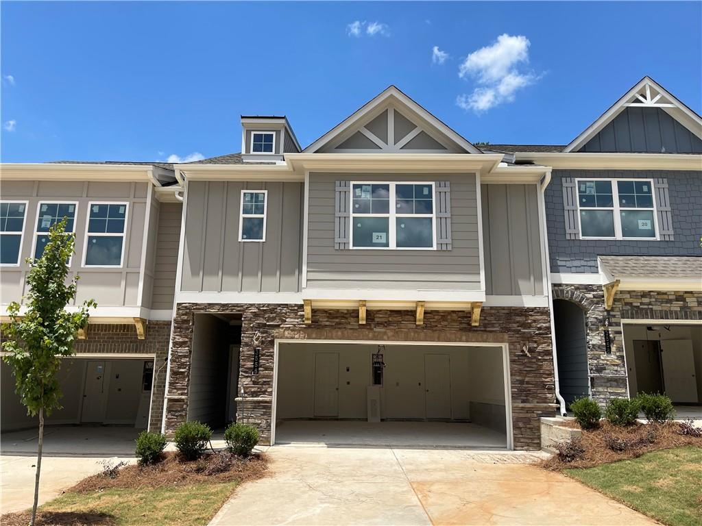 Multi-story townhome exterior featuring stone veneer accents, vertical and horizontal siding, and multiple gables
