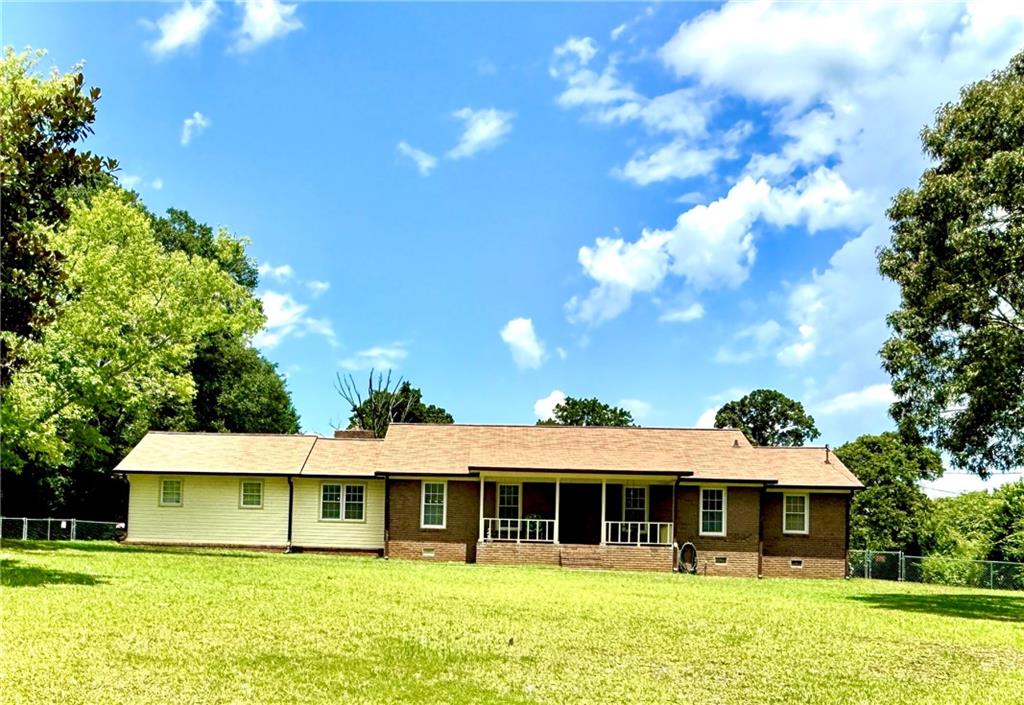 harming 4-Sided Brick Ranch on a Private 1-Acre Lot! Welcome home to this beautifully maintained 3-bedroom, 2-bath ranch nestled on a spacious, wooded 1-acre lot offering privacy and tranquility. This solid 4-sided brick home features a large eat-in kitchen equipped with stainless steel appliances-perfect for family meals and entertaining. Enjoy multiple living spaces with a generous living room and a cozy den/family room ideal for gatherings. Step outside to relax on the inviting front porch complete with a classic porch swing, or unwind on the covered back porch overlooking the fenced backyard. Car enthusiasts, hobbyists, or those needing extra storage will love the oversized 2-car garage, large workshop, and multiple outbuildings-including a storage unit big enough to park an RV or boat, plus two additional smaller workshops/storage sheds. Book your showing today before this one gets away! Don't miss this unique opportunity to own a well-cared-for home with space, storage, and peaceful surroundings-all just minutes from local conveniences. Don't delay, schedule your showing today!