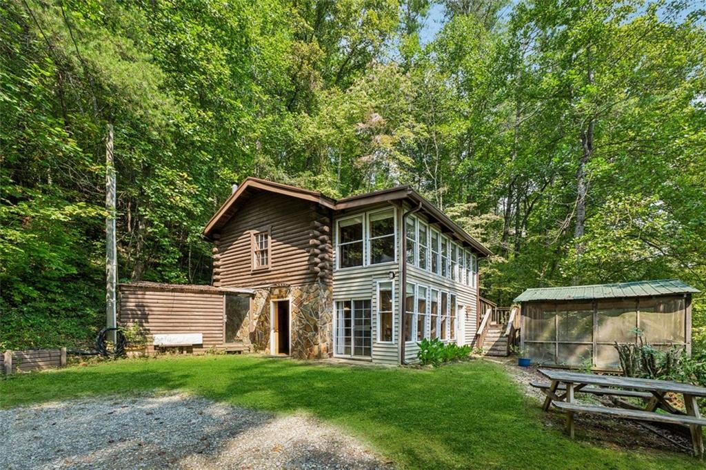Welcome to Hidden Valley! This charming cabin in the mountains has been lovingly named “Rabbit Hill”. It sits on the Little Mountaintown Creek. That’s right, not only can you sit out in the screened in porch and listen to the creek while sipping your morning coffee, but you can also walk down for fishing or tubing in the water because your land goes to the center of the creek! Inside the home you’ll find a large living space on the main floor with a full bathroom, kitchen and dining areas, as well as a laundry room space. Head upstairs for the 2 bedrooms and another full bathroom, in addition to a large, enclosed sunroom space! Outside, if you aren’t spending time in the screened in porch space, you can find a green house type structure next to the home, and a covered carport structure with 2 parking spaces, as well as an enclosed area for storage or workshop space. This home offers tons of character and could be used as either a primary residence or a STR as there are no HOA’s or rental restrictions, and a short drive to downtown Ellijay! Come see all this mountain waterfront property has to offer!