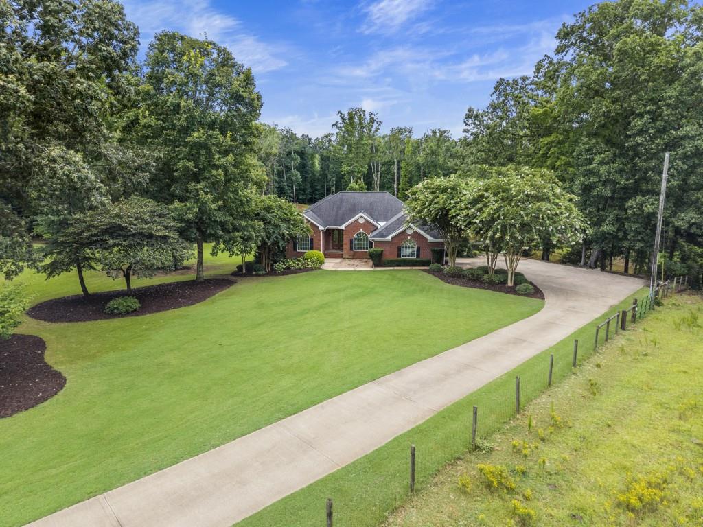 Welcome to this stunning custom-built home nestled on 9.22 acres of absolutely beautiful land in the heart of Newton County. With 3 spacious bedrooms and 3.5 bathrooms, this gated property offers privacy, charm, and modern comforts all in one. From the moment you arrive to the beautiful gate with classic oil lanterns, you'll be captivated. The paved driveway only sets the tone for the warmth and elegance found throughout the home. Inside, the remodeled kitchen is a chef's dream, featuring double ovens, a striking copper sink, and both an eat-in kitchen and formal dining room-perfect for entertaining. The stone fireplace anchors a cozy family room adorned with plantation shutters, adding timeless southern character. The finished basement offers flexible living space with its own eat-in kitchen, living area, private room (ideal for a bedroom or office), and a full bath-perfect for guests, in-laws, or multi-generational living. Step outside to take in the breathtaking, landscaped 9.22 acres, complete with a one and 1/2 acre peaceful pond, stocked with bream and bass, and a sparkling pool. The 20 x 20 pool house includes a kitchenette, full bathroom, fireplace and electric cool screens, making it an ideal space for entertaining summer gatherings and football parties. The 30 x 40 shop, with power, is perfect for work or play. The 6 inch, fiber-infused concrete drive was built for heavy equipment. The possibilities are endless here. Don't wait to schedule your private showing.