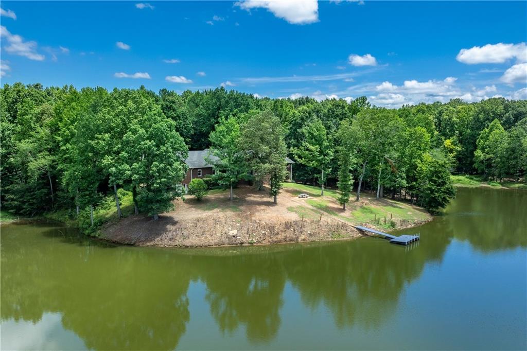 One of a kind property! Four board fence lined with mature fruit trees along paved Harris Road creates inviting entrance to property. Enter through large metal gate between brick Collums and magnolia trees down a 1000 foot paved private drive to the hidden 4-sided Brick ranch home that sits on private knoll overlooking gorgeous 4 acre lake with large private dock. Lake is fully stocked with healthy population of Bass, Catfish and Bluegill that produces trophy catches. Property is a sportsman's paradise with wooded area in back that is home to whitetail deer and turkey for healthy wild game opportunities. Home features 4 extra-large bedrooms and 4 1/2 Baths. Gorgeous hardwood floors and trim features that include fluted door jams, crown molding and solid wooden doors throughout the home. Gorgeous masonry fireplace in family room. Large formal dining room and separate den/office room if you work from home. Sunroom with stone floor spans along the back of home overlooking rear park like setting and gorgeous lake and party dock. Country kitchen features island and liberal counter space for the chef in the family. Large laundry room on main level has mud sink and cabinetry for extra storage. Full basement is unfinished but offers bathroom and canning kitchen with a secure storm shelter with concrete ceiling that could be converted into a gun vault. High basement ceilings and large open area lends space for the ultimate man cave or in-law suite with garage door and private driveway access. 40 x 50 clear span barn/shop is insulated with full bath, tack room, work bench, high rollup doors and heat unit. Also has 10 x 50 covered front shed with concrete floor in front along with shed on back that would easily convert to equestrian stalls. Pasture in front now used for cattle would make nice paddock or riding ring area for horses. So much to mention it would be easy to forget about the hidden one room fish cabin on the back side of the lake hidden from the outside world! Great place for that off the grid experience to offer friends or family members up for the weekend! This 45 acre investment with the lake as a wonderful centerpiece offers many possibilities!