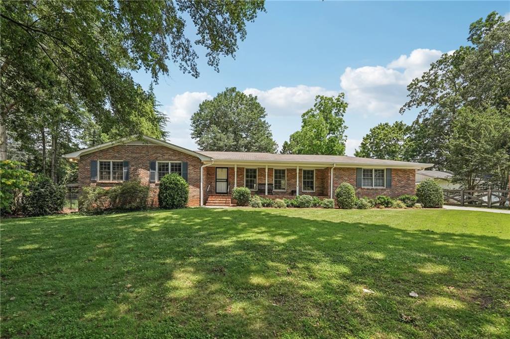 Welcome to 1501 Memory Lane SE, a beautifully updated brick ranch on a lush 0.75-acre lot in a serene, tree-lined neighborhood. This timeless 3-bedroom, 2-bathroom home spans 1,949 sq?ft and welcomes you with hardwood floors throughout, an inviting two-sided brick fireplace connecting the cozy family room and bright sunroom, and a chef-inspired kitchen featuring gray cabinetry, stone counters, a tile backsplash, stainless appliances, a generous pantry, and built-in writing desk. The spacious primary suite boasts an updated bathroom with a step-in tile shower. A large laundry room with sink and storage adds everyday convenience. A rare attached one-car garage complements a carriage house in the back, which offers an additional 300?sq?ft of living space with 1 bedroom, 1 bath, and its own garage. Downstairs, a spacious unfinished basement offers room to grow. Outside, enjoy the private patio (complete with a natural gas line for grilling), a large garden shed wired for electricity, and a peaceful yard of mature trees that’s ideal for outdoor living. Close to parks and walking trails, this home seamlessly blends modern comfort, versatile space, and tranquil neighborhood charm.