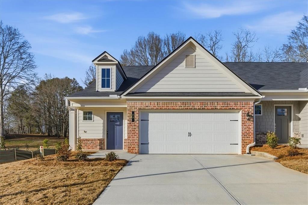 View of front of house with covered porch, brick siding, an attached garage, and driveway
