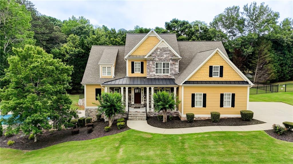 Modern Elegance Meets Resort-Style Living in Providence Lake - Get ready to fall in love with a home that truly has it all-luxury, comfort, and the ultimate staycation lifestyle! Perched perfectly on a gentle rise in the prestigious Providence Lake community, this Mediterranean-inspired beauty blends timeless Southern charm with bold design and exceptional functionality. With summer around the corner, the backyard oasis is calling your name! Elevated on a beautifully landscaped lot, this home makes a grand first impression with its stately front porch, classic columns, and commanding view. The show-stopping heated saltwater pool and hot tub turn every day into a vacation. Whether you're lounging poolside, hosting a BBQ, or soaking under the stars, this private retreat is made for year-round enjoyment but there's no better time than NOW to make it yours! Step inside to find gorgeous hardwood floors throughout, rich chocolate and warm gold tones, and luxurious touches like 12- and 18-inch crown molding, coffered ceilings in the family room, and a trey ceiling in the owner's suite. Classic wainscoting adds timeless detail to both the main and terrace levels. The main-level owner's suite is a true sanctuary, featuring a stunning, multi-layered tray ceiling with intricate molding that adds depth, dimension, and a custom designer touch. It's a space that feels both luxurious and serene-perfect for unwinding at the end of the day. Enjoy cozy nights by the fire with two custom fireplaces-each featuring hand-crafted mantels and magnificent stonework that make a bold statement. The chef's kitchen features custom cabinetry, a dramatic designer vent hood, granite countertops, and a massive eat-in island. Flowing effortlessly into a charming keeping room and sunlit breakfast nook, this space was built for gathering. The terrace level, finished by the original custom builder with high ceilings and the same premium quality as the main floor, this level includes a spacious family room, private bedroom, office, fitness area, spa room, and both a full and half bath-each with quartz countertops. A stunning kitchenette with a quartz galley island and modern gray tones makes this space ideal for guests, multi-generational living, or entertaining in style. Currently used as a media room, the upstairs elevated great room is the ultimate flex space. Whether you turn it into a game room, a hangout for teens, or a cozy gathering spot for movie nights and weekend fun-this room brings the "WOW" and the possibilities. When you tour this home you will find smart stylish details everywhere! Plantation shutters throughout-including in the garage-add charm and privacy. Custom built-ins in the relaxation room, media room, and living areas add sophistication and functionality. Walk-in closets in every bedroom ensure plenty of storage space. Upstairs also features three additional spacious bedrooms, a spacious bonus room, and flexible living options for every lifestyle. The finished terrace level and heated saltwater pool are both less than three years old, offering modern efficiency and peace of mind. Plus, a transferable home warranty through March 2026 provides added value and security for the next homeowner. Seller is relocating and priced this beautiful home right! You simply won't find another move-in ready home at this price point with this level of custom finishes, space, and amenities. Don't miss your chance to make this extraordinary property yours-schedule your private showing today!