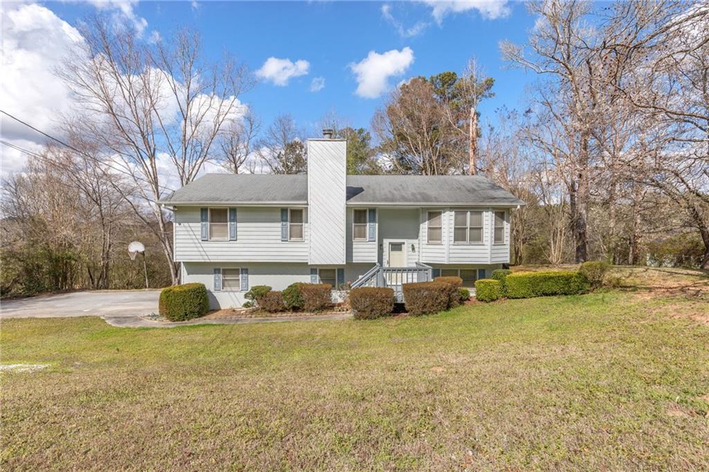 Raised ranch featuring a chimney and a front yard