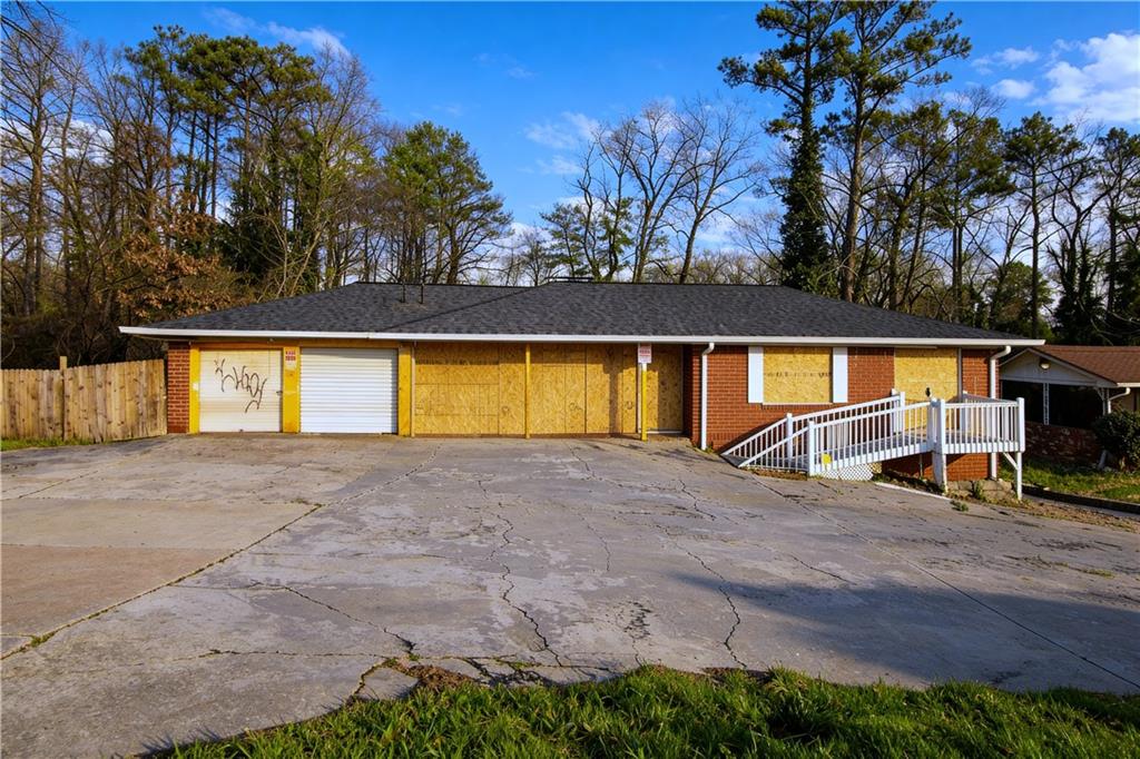 Ranch-style house featuring brick siding, concrete driveway, a garage, and roof with shingles
