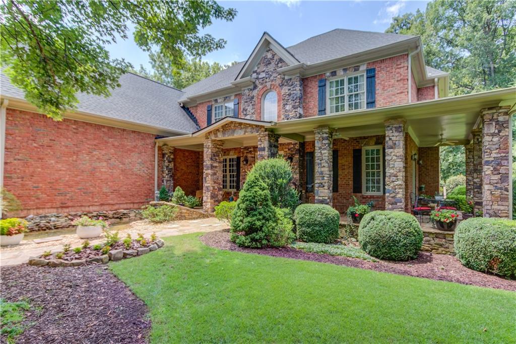 Located in the prestigious Woodlands section of Château Élan, this stunning 6 bedroom, 6.5 bath estate offers exceptional space, custom finishes, and ultimate privacy on a beautifully landscaped cul-de-sac lot. Thoughtfully designed, this home features coffered ceilings in the office and living room, four gas fireplaces, and a main level guest suite. The open concept kitchen is a chef’s dream, boasting a 6 burner Smeg cooktop, double ovens, built-in steamer, light colored cabinetry, walk-in pantry, and views of the cozy keeping room with a pine ceiling and stacked stone fireplace. Upstairs, the oversized owner’s suite impresses with a massive walk-in closet complete with its own washer/dryer connections. Four additional bedrooms and two full baths complete the upper level. The expansive finished terrace level offers endless possibilities with a full bar, stacked stone accents, built-ins, fireplace, theatre room, two full bathrooms, a pet-friendly laundry room with a wash sink, generous storage, and a fully equipped workshop with upgraded 220V power. A spacious 4 car garage provides ample room for vehicles, golf carts, and storage. Enjoy quiet mornings or evening gatherings on the wraparound front porch or the private, wooded backyard retreat with a partially covered back porch and space left for a future pool. As part of the Chateau Elan Community, enjoy resort-style amenities including three golf courses, a sports club complete with a gym and basketball court, swimming pool, on-site winery, full-service spa, and multiple restaurants. With laundry on every level and upscale details throughout, this home blends elegance and comfort in one of North Georgia’s premier gated communities.