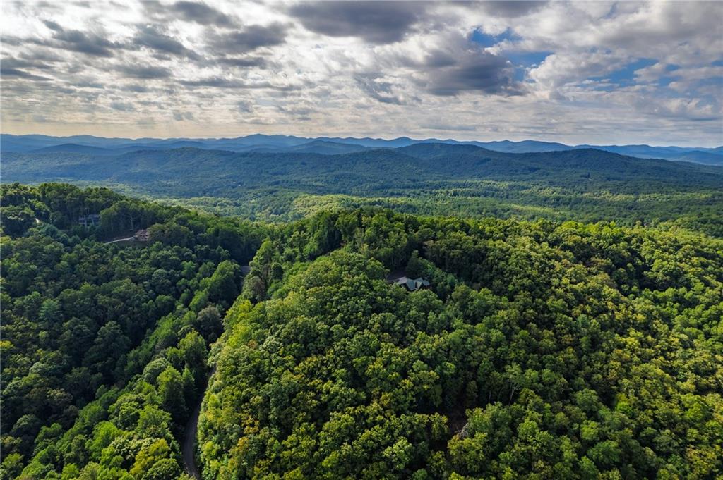 Welcome to Nature’s Courtyard in Mineral Bluff, Georgia, home to this breathtaking 5.32-acre parcel, nestled in the Blue Ridge Mountains with spectacular long-range views, peaceful privacy, and some of the groundwork already complete. Ready for your mountain dreams to begin?
Located just minute from NC, 15 miles from downtown Blue Ridge, 17 miles from Blairsville, and only 11 miles to Lake Blue Ridge, this gated community offers the perfect blend of mountain seclusion and modern convenience. You'll enjoy paved roads all the way to your driveway, underground utilities, community water access, and high-speed fiber internet available. Yes, even way out here.
You’re just minutes from the fun, shopping, and dining in Blue Ridge, and a short drive to Blairsville’s restaurants, shops, and hospital.
This particular lot offers something special, a buildable home site with room to grow. Whether you envision a custom mountain home, a peaceful family retreat, or space for an outbuilding, workshop, or detached garage, you have options. Soil work is already complete. A rough driveway has been cut in. The land is rolling but usable, with stunning views that could be opened up even more with a little vista pruning.
Nature’s Courtyard is a place where homes are built to complement nature, not compete with it. Protective covenants preserve the peaceful, natural feel of the community. No mobile homes, no commercial businesses, no clutter. Just beautiful homes that blend with the mountain setting.
Homes here must be a minimum of 1,400 square feet of heated living space, ensuring a standard of quality and value throughout the neighborhood.
Already own an RV? You are welcome to bring it, as long as it is stored in the rear yard. You can even use it for up to 10 days per month for recreational stays before your home is built. It is an ideal weekend base while you plan your mountain build.
And let’s talk lifestyle. Whether you're looking to exchange the flatlands for mountain peaks, unplug from the busy city pace, or start fresh in the North Georgia mountains, this is the kind of place where you can sip your coffee while the sun rises over rolling hills, breathe in the fresh air, and actually hear the quiet.
If you've been searching for a peaceful, view-filled property that's ready to go, but without the restrictions of a cookie-cutter neighborhood, Dusty Danno Trail might just be your next great escape.