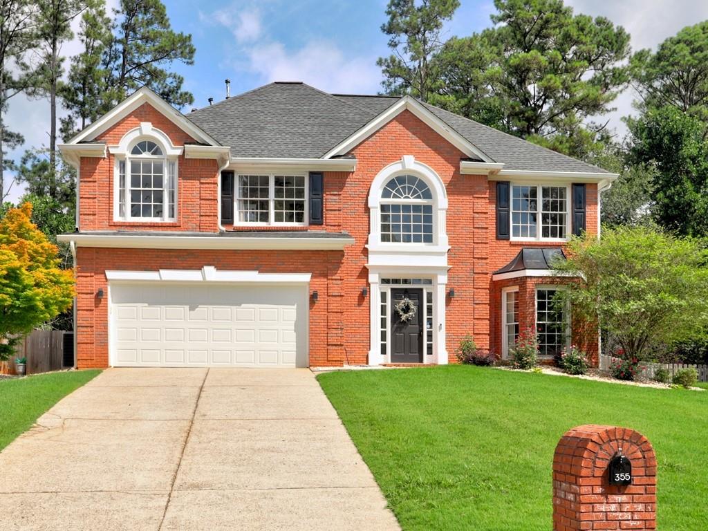 Brick facade residence with a two-car garage, arched entry window, bay window, and a brick mailbox