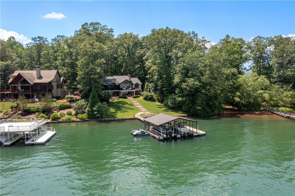 Introducing a stunning waterfront retreat at 1611 Heathers Cove Rd, Hiawassee, GA – a newly listed, architecturally designed gem nestled beautifully with breathtaking views of the Appalachian Mountains. This exquisite property, masterfully renovated by designer Mike Swilley and Jerry Kyle Construction, spans a generously appointed landscape with top-tier finishes and remarkable attention to detail.
Enter through an inviting foyer that seamlessly transitions into a vaulted family room adorned with century-old Indiana beams and a cozy fireplace. The home boasts a chef's dream kitchen with vaulted ceilings and equipped with integrated Subzero appliances, superb marble countertops, and a secondary scullery. Comfort and luxury define the main-level master suite, featuring a romantic fireplace, awe-inspiring views, and an ensuite bath complete with a large shower, soaking tub, heated floors, and double marble vanities.
Additional accommodations include a guest suite with a luxury bath on the main floor, alongside practical spaces such as a study, laundry, and half-bath. The hardwood-covered main level flooring and shiplap walls lead to a terrace level that enhances living with a large family room, equipped with a wet bar with subzero refrigeration and freezer drawers, two additional guest suites with ensuite baths, and another half-bath. Travertine floors add to the ambience.
Exterior features include an expansive outdoor living area with a fireside porch, sun deck, grilling area, and a stone patio complete with a hot tub, fire pit, and bed swings. The custom-covered dock offers two boat slips with lifts and jet ski pads. Home is situated on a deep water lot.
Additional features of the home include a whole house generator, Control 4 system, tankless water heaters, motorized screens, irrigation system, custom window treatments, security system, storage building, and circular driveway.
This property is a must see and is conveniently located, providing both serene isolation and access to community amenities. Perfect for those seeking a luxurious, peaceful lifestyle by the water. Experience the epitome of lakeside living in this magnificent Hiawassee home.