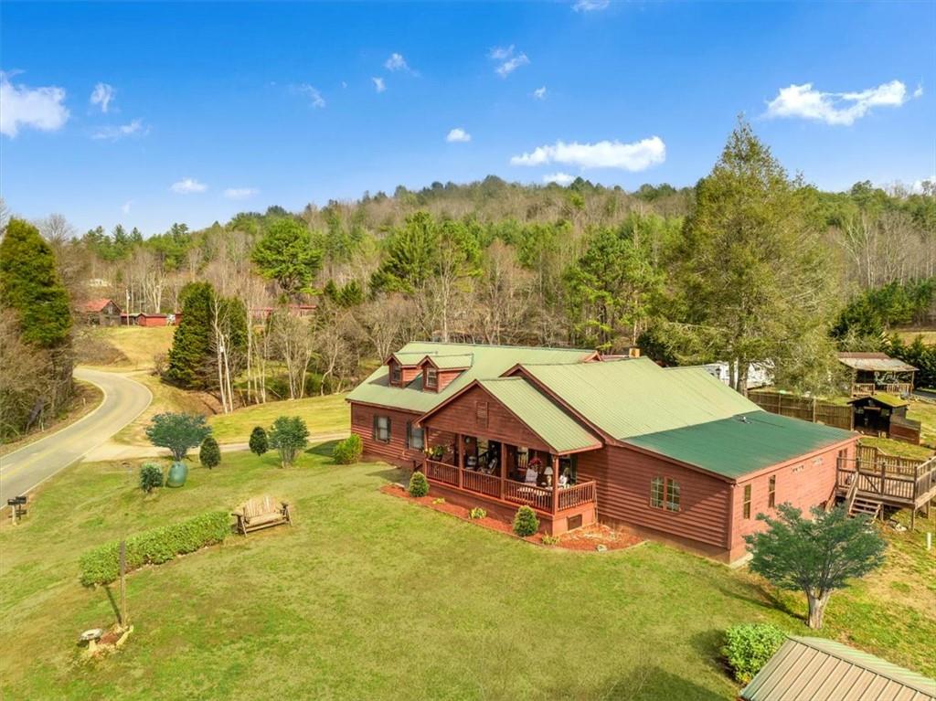 Charming Georgia Mountain Retreat with Modern Comforts and Unbeatable Views surrounded by hundreds of acres of National Forest! Welcome home and come explore this enchanting rustic home that perfectly blends original character with modern luxuries. Offering breathtaking mountain views, this spacious five-bedroom residence is an ideal setting for both relaxation and entertaining. The newly added primary suite features an en-suite bathroom, a large walk-in closet, and a flexible space that can be used as an office, nursery, or bedroom. At the heart of the home is a beautifully appointed kitchen, complete with a coffee bar and an oversized island that comfortably seats six or more guests, making it perfect for hosting. Outside, the property boasts a pond with a creek, lush fruit trees-including apple, peach, fig, and pear-and beautiful dogwood and persimmon trees. The welcoming wrap-around deck offers a private oasis where you can enjoy stunning views, the serene sounds of the creek, and a peaceful fishing pond. This property also includes multiple outdoor structures, such as an expansive barn with stalls, a workshop, a pole barn, a charming artist's shed with built-in bunks, a storm shelter, and a historic smoke shed. The fully fenced area offers privacy and security for pets, a garden, or a playground. Located near Lake Chatuge, enjoy easy access to boating, fishing, swimming, hiking, and camping. Explore nearby attractions like Helen, Unicoi State Park, Anna Ruby Falls, Marina Station Water Park, North GA Fairgrounds and tubing-all within a 25-minute drive. About 40 minutes away you will find the Cherokee Valley Casino. With a newly installed HVAC system, a new septic system, and a complete list of upgrades, this home is a true blend of historic charm and modern comfort. This unrestricted property is ready for you to make it your own. Don't miss the opportunity to experience mountain living at its finest!