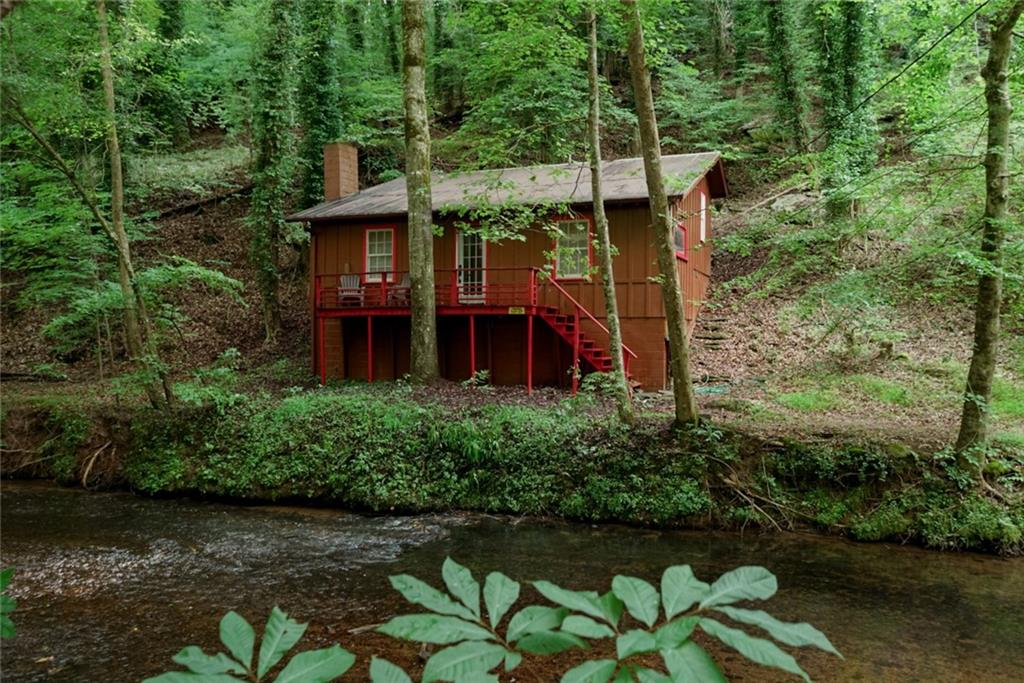CREEKSIDE SERENITY WITH THE SOUNDS OF CANE CREEK WATERFALL! – Your North Georgia Mountain Retreat
Only minutes from the heart of Dahlonega, Restaurants, Wineries, Hiking Trails, and more! This charming cabin offers the perfect blend of rustic comfort and natural beauty. Situated directly on a pristine mountain creek, the property features a large breathtaking waterfall just steps away—visible from your front porch and audible day and night, creating an atmosphere of peace and tranquility. Whether you're looking for a part time escape from the hustle and bustle of the city or a high-demand short-term rental, this cabin checks all the boxes! Imagine waking up to the sound of cascading water, sipping coffee on the porch as mist rises from the creek, and ending your day with the soft glow of fireflies dancing along the water’s edge. This property is privately deeded and is not considered part of Camp Glisson, yet you have the peace of mind of a gated community. As you enter the home you will find a cozy Living Room with Vaulted Ceilings Open to the Kitchen/Dining area with beautiful views from every window. Just a few stairs to the Split 2 Bedrooms separated by a Full Bathroom with a claw foot tub/shower. Don't miss out on the RARE opportunity!