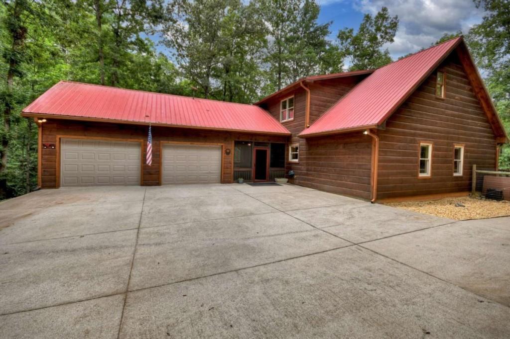 Discover rustic charm and timeless mountain living on 1.55 serene, unrestricted acres in the heart of Cherry Log. Immaculately maintained and rich in character, this spacious cabin offers over 3,800 sq ft of heated living space, with 4 bedrooms, 3.5 baths, and flexible spaces thoughtfully designed for comfort, entertaining, and everyday living. The inviting great room features soaring ceilings, a dramatic floor-to-ceiling stone fireplace, and warm wood finishes that reflect true mountain craftsmanship. The generous dining area flows into a beautifully updated kitchen with brand-new quartz countertops, custom cabinetry, and soft-close drawers-ideal for gatherings both big and small. The main level includes two spacious bedrooms and two full baths, while the upper level offers two additional bedrooms, a full bath, a large sleeping loft, and a massive attic that could easily be finished for more living space. The fully finished terrace level is a standout with its rich rustic design, offering a cozy living area, custom bar, wine cellar, and a library/game room that could serve as a 5th bedroom or private retreat, along with a half bath. This level would also make a fantastic in-law suite or private apartment, with its own spacious layout and entertaining amenities. Step outside to enjoy the screened-in breezeway, a peaceful extension of the living space, perfect for relaxing or dining al fresco. The beautifully landscaped grounds offer a tranquil backdrop, complete with a firepit area-ideal for stargazing, storytelling, and making memories. The finished 2-car garage with tongue-and-groove walls provides additional storage and charm, and a whole-house generator ensures year-round peace of mind. Lovingly cared for and move-in ready, this home is an ideal full-time residence, weekend escape, or rental investment-where nature, comfort, and mountain beauty converge.