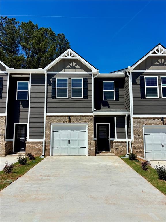 Craftsman house featuring board and batten siding, driveway, a garage, and brick siding