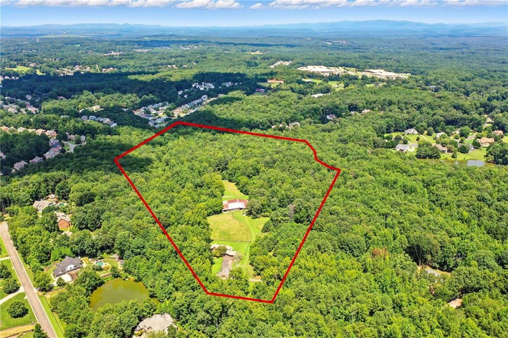 Nestled at the end of a quiet country lane, this idyllic 36-acre property presents a rare opportunity in the highly sought-after Creekview High School district, just minutes from Milton and Alpharetta. Surrounded by estate properties, this private tract blends natural beauty with endless potential.
The land features open meadows, mature hardwoods, a flowing creek, and multiple building sites, making it ideal for a private estate, equestrian retreat, or future development. Whether on horseback, ATV, or foot, you’ll enjoy scenic trails winding through the woods and along the creek.
Equestrian facilities are already in place with fenced and cross-fenced pastures, a 30-stall barn, large arena, and round pen. The barn is thoughtfully designed for efficiency and accessibility, with easy trailer turnaround, designated parking, two offices, a bathroom, multiple tack and feed rooms, hay and shavings storage, and tractor storage: everything needed for a fully operational horse or livestock farm.
The residence offers vaulted and beamed ceilings, heart of pine flooring, a cozy fireplace in the primary suite, spacious kitchen, sunroom, and screened porch. With 3 bedrooms, 2 full baths, 2 half baths, a bonus room over the garage, and a workshop, the home provides flexibility—perfect as a barn manager’s home, a remodel opportunity, or a suitable place to live while you build your dream estate.
This property is truly one-of-a-kind. Whether you envision a private estate, family compound, or development opportunity, you won’t find another 36-acre parcel with this much potential in such a prime location. Additional acreage on Pat Rich Road is also available to possibly create a larger development tract.
Seller will consider Owner financing