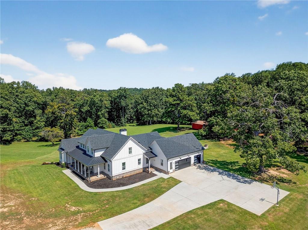 Experience the perfect blend of modern luxury, farmhouse charm, and ultimate privacy on this rare 11.33-acre gated estate fully fenced and thoughtfully designed, this property offers the best of both worlds—peaceful country living with easy access to everything you need. Inside, an open floor plan welcomes you with vaulted beam ceilings and elegant luxury vinyl plank flooring. The chef’s kitchen is a true showstopper, featuring top-of-the-line KitchenAid stainless steel appliances, a six-burner gas stove, leathered granite countertops, custom cabinetry, and a classic farmhouse sink. Accordion-style doors extend the living space outdoors to a covered patio, saltwater pool, gas fire pit, and over 1,050 sq. ft. of decking—ideal for entertaining and indoor-outdoor living. This home boasts six spacious bedrooms, including four on the main level with ensuite baths. The oversized master suite is a serene retreat, while upstairs you will find a versatile loft and additional bedroom with full bath. The finished terrace level is thoughtfully designed for entertaining, complete with a full kitchen, large recreation room with bar, bedroom suite, workout room, half bath, and its own laundry—perfect for in-laws, teens, or guests. The 3 car side-entry garage comes EV-ready and connects to an extended driveway with ample parking. For equestrian enthusiasts, the property includes a 3-stall barn with water and electricity, flowing pastureland, and a creek. Efficiency meets convenience with a tankless water heater, well water, septic system, water softener, and a 300-gallon propane tank powering the stove, fireplaces, fire pit, grill, and generator. This one-of-a-kind property delivers tranquility, space, and luxury in a prime location—making it a truly rare find!