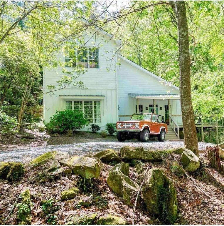 This truly one-of-a-kind property offers an irreplaceable setting as it is nestled just feet from a year-round cascading waterfall and a creek that runs the full length of the expansive back deck. Homes with a natural feature like this are nearly impossible to find in today’s market, and the serene beauty of this setting can not be replicated through new construction. Inside, the home features 3 bedrooms, 3.5 baths, plus a versatile fourth room ideal for use as a guest bedroom or office. The open floorplan is perfect for entertaining, enhanced by a wet bar, spacious living and dining areas, and seamless access to the large back deck—ideal for gatherings or peaceful outdoor living. The oversized master suite impresses with high ceilings and ample space, while the sunroom offers the perfect retreat to relax with breathtaking views of the creek and waterfall. Additional highlights include a 3-car garage and a separate outbuilding that could be utilized as a workshop or for extra storage. Conveniently located with quick access to GA 400, this home combines natural beauty, functionality, and convenience - making it a rare opportunity for both everyday living and entertaining. The home is currently being used as a rental. Please do not approach the home or access the driveway area unless a showing has been scheduled (as a courtesy to the current renters).