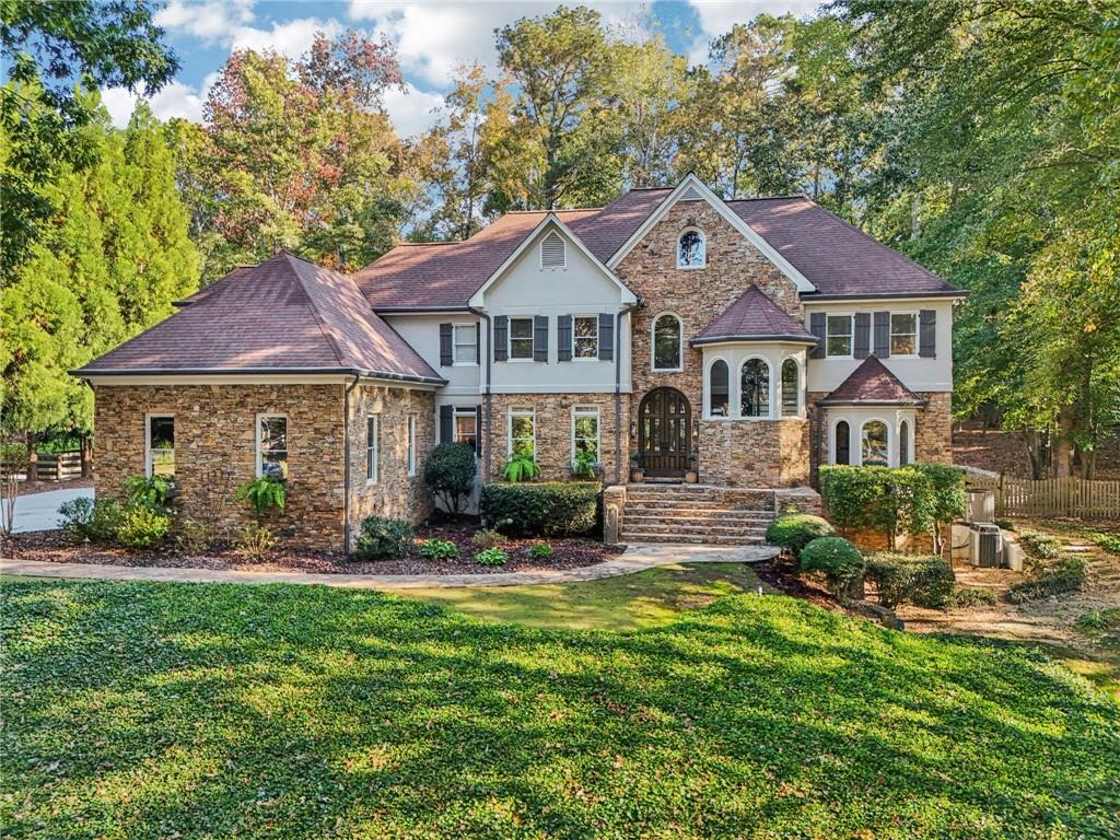 Exquisite French Country estate designed by renowned architect Stephen Fuller—a masterpiece of timeless elegance and luxury living. From the grand two-story entryway with dual staircases to the richly detailed coffered and trey ceilings, hardwood floors, and intricate trim work, every inch of this home exudes sophistication. The updated kitchen is a chef’s delight, featuring stainless steel appliances, granite countertops, a gas range, and a wall oven. The spacious kitchen and breakfast room flow seamlessly into a bright sunroom, perfect for relaxed mornings or entertaining. An oversized pantry with a second refrigerator provides exceptional storage and convenience. The primary suite with fireplace and a recently remodeled spa-like bath offers a serene retreat, while upstairs you’ll find three additional bedrooms and two full bathrooms, providing ample space for family or guests. The finished terrace level is an entertainer’s dream, complete with a pub-style bar, theater room, guest suite, and full bath. Enjoy the warmth and ambiance of four fireplaces throughout the home, each adding charm and comfort to the living spaces. Step outside to the private, professionally landscaped backyard surrounded by evergreens and featuring flagstone walkways, a sparkling pool, and a relaxing spa—your personal oasis. Located in the sought-after Polo Golf and Country Club, within walking distance to Vickery Village, and just minutes from Cumming City Center, Halcyon, Big Creek Greenway, top-rated schools, and premier shopping and dining. With luxurious finishes and exceptional craftsmanship throughout, this residence offers both grandeur and warmth in one perfect package.