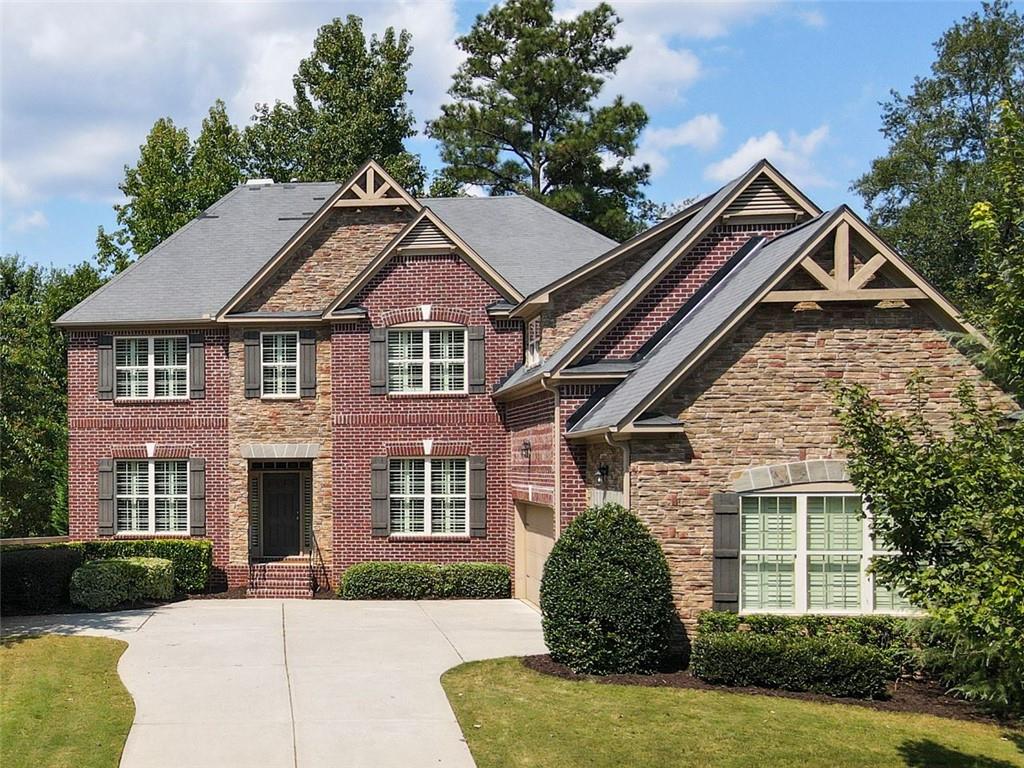 Welcome to this beautifully designed home offering space, style, and convenience in one of the area’s most desirable swim/tennis neighborhoods. Step into the main level, where a private office sits to the left and a formal dining room to the right, creating the perfect blend of function and elegance. The heart of the home is the open-concept living area, featuring a dramatic two-story wall of windows, a stunning stone fireplace with built-in surround, and seamless flow into the spacious kitchen and breakfast room. The kitchen is as practical as it is inviting, with plentiful cabinetry, a pantry, bar seating at the island, and easy access to the garage. Step out from the breakfast area onto the deck, offering both covered and uncovered spaces ideal for year-round outdoor entertaining. A main-level bedroom with a full bath makes a perfect guest suite or multigenerational option. Upstairs, retreat to the luxurious primary suite with vaulted ceilings, an attached sitting room, and a spa-like bath boasting a huge shower, separate soaking tub, and dual vanities. Three additional bedrooms upstairs include one with its own private bath and two connected by a jack-and-jill. The unfinished terrace level, already stubbed for a bath, is ready for your personal touch, whether you envision a media room, home gym, or additional living space. Outside, the beautifully landscaped yard enhances the home’s curb appeal and provides a peaceful backdrop. All of this is located just minutes from Avalon, Downtown Alpharetta, and Milton’s charming shops and dining, with easy access to top-rated schools and community amenities.