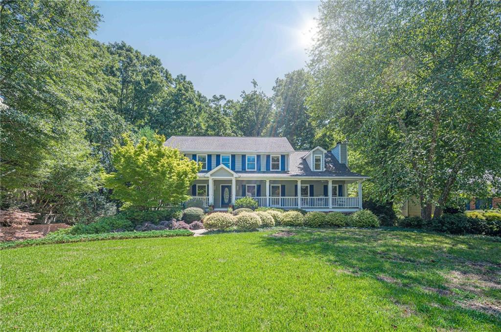 Nestled in a serene, wooded setting with the peaceful sound of a bubbling creek just beyond the backyard, this gracious traditional home offers everything you need to move right in and fall in love. With its inviting rocking chair front porch stretching across the entire front of the home, it’s the kind of place where morning coffee tastes better and evenings invite sweet tea and conversation. This home is ready for the next owner to fall in love, to add their personal touches and make it their own. Step through the front door into a welcoming hardwood foyer, setting the tone for the abundant space throughout. To your left, the formal living room is the perfect canvas — ideal as a music room, home library, or quiet study. To the right, the formal dining room is ready to host holidays, dinner parties, or weeknight meals alike. At the heart of the home, the spacious kitchen delivers both charm and function with plentiful cabinetry, a center island, a built-in desk, and a pantry. You’ll love the stainless steel appliances, including wall oven/microwave combo, new electric cooktop, and dishwasher, making it easy to settle in and start cooking. The sunny breakfast room, framed by a bay window, overlooks the private, wooded backyard — a perfect spot to birdwatch over brunch. The fireside family room is a cozy retreat with a wood-burning brick fireplace, raised hearth, and warm ambiance, inviting you to curl up with a good book or gather with loved ones. A main floor bedroom with a private entrance to the full tiled bath offers ideal space for guests, multigenerational living, or a private office. The main floor also features a separate laundry room, with storage and a washer and dryer that remain with the home. Upstairs, the oversized primary suite is a true sanctuary, complete with a sitting room and tranquil bay window overlooking the lush backyard. The expansive en suite bathroom features a vaulted ceiling, skylight, separate shower and water closet, soaking tub, make-up vanity area, double sinks, and two enormous walk-in closets — plenty of room to dream and design your ideal spa retreat. Two additional spacious bedrooms share a tiled hall bath and hall linen closet. The finished basement offers a world of potential — home theater, office, gym, game room, playroom — with a tiled half bath (plus closet and sump pump) and two sets of French doors opening to the lush backyard and covered patio below the main-level deck — perfect for al fresco dining, relaxing, or entertaining. A drive-under, side-entry 2-car garage includes even more space for storage, a workshop area, and a separate door to the backyard. With Hardiplank siding, abundant storage throughout, and beautiful setting, this warm, well-maintained home is ready for its next chapter — and its next lucky owner. Come make it yours!