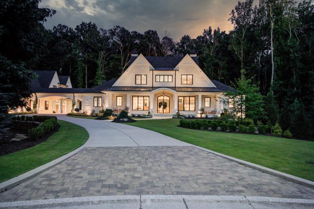 The most exquisite estate in all of North Atlanta is located in Suwanee's prestigious The River Club! Designed by Visbern Architects and built by Culver Homes, this estate is second to none!  As a winner of two national building and design awards, this home is everything you would expect and more in a home of distinction.  The home sits on 1.384 acres, cul-de-sac, park-like setting, completed with 4 sides Texas limestone, welcoming front porch, and a Porte-de-Cochere with a motor court. The street presence is simply magnificent!  When you enter through the steel glass front doors, you will stand in amazement seeing through the expansive space that encompasses the Family Room, Dining Room, Gourmet Kitchen, and Breakfast Room.  The main floor also boasts a private home office, a caterer's kitchen/pantry, and a serving bar to the fireside sunroom complete with heated floors.  The Primary Suite is located on the opposite side of the main and has a very Zen relaxing bathroom with a custom refreshment bar and curved brick ceiling.  The sitting area leads to the primary suite with 3 sides of pure glass to the private backyard.  For entertainment purposes, the television is on a lift system that raises and lowers it into the floor when not in use.  The laundry room on the main features a wash basin, grass cloth wallcoverings, and custom cabinetry to include drying shelves built in!  This is one of 3 laundry rooms throughout the residence. The Kitchen is designed for a chef with 2 tower refrigeration/freezer; 60-inch cooktop; and a large working island with a sink and a view to Family Room.  The Family Room features a limestone fireplace, custom built-ins, and panoramic sliding doors to the walk-out level pool!  An elevator completes the modern conveniences! The second-floor houses 3 generously sized guest suite bedrooms with private baths.  The terrace level is a work of art!  The Media Room focuses on a quartz wall with a ribbon fireplace and custom cutouts for showcasing art pieces.  The massive home gym is state of the art with brick and mirrored accent walls.  There is also a refreshment bar and custom lockers.  This room could easily be converted to an additional bedroom.   Down the hall you will find both a dry sauna and a steam sauna.  Hobby rooms and lots of storage.  A sample of upgrades includes retractable screens on the patio with infrared heaters; hardwood floors throughout; Marvin windows and Doors; an irrigation well; a Crestron system; Lutron lighting; a whole house filter system and upgraded HVAC systems.  The oversized 4-car garage hosts a carriage house with elevator access.  The carriage house is self-sufficient with a Great Room, Breakfast Area, full Kitchen, and Bedroom with full Bath.  This suite is perfect for multi-generation or caretakers.  This home offers the walk-out main pool with pool bath, English flower garden, outdoor kitchen, fireside chat area, and a putting green all on a private homesite!  This is quality construction with resort living!