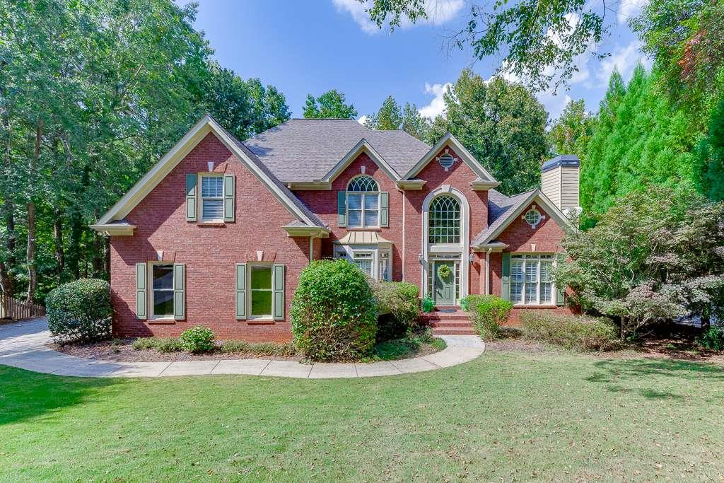 Welcome to this beautifully appointed 2-story home featuring a brick front, full finished basement, and serene wooded backdrop. Inside, hardwood flooring flows throughout the main level and upstairs hallway, complemented by brand-new carpet in the bedrooms. The gourmet kitchen is a chef's dream with granite countertops, stainless steel appliances, a custom-designed island, and a walk-in pantry with a custom shelving system. A keeping room with a two-sided fireplace seamlessly connects to the inviting family room, creating the perfect setting for gatherings. The oversized primary suite is conveniently located on the main level and offers a fireside sitting area-ideal for an office or quiet retreat. The updated spa-like primary bath showcases dual vanities and an enlarged, custom-tiled shower. Upstairs, one secondary bedroom features a private ensuite with hallway access, while two additional bedrooms share a Jack-and-Jill bath, each with separate sink vanities. The terrace level is partially finished and designed for entertaining, complete with a custom kitchenette/bar, ensuite bedroom with a sitting room, and an extended patio overlooking the wooded lot. The unfinished section of the lower level offers ample storage space and workshop area. Additional highlights include a newer Lennox A/C unit on the main level, an active neighborhood association, and a prime location near the Chattahoochee River trails, schools, shopping, and dining. This home effortlessly combines luxury, comfort, and convenience-don't miss the chance to make it yours!