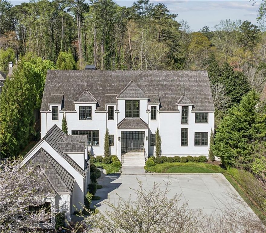 Tucked within a landscape of understated splendor lies a home that feels conjured from the pages of an architectural fairytale - a place where timeless design and modern luxury meet in perfect harmony.  Beyond its gracious fa ade, through arched entryways and steel-framed doors, the home invites you into a world curated with natural stone, warm wood, and whispers of elegance at every turn. Each corner reveals an artisan's touch - a celebration of craftsmanship and refinement.  The main level unfolds like a grand but welcoming salon: soaring 12-foot ceilings stretch above herringbone-laid hardwoods, as rooms ebb and flow with a rhythm made for both everyday comfort and effortless entertaining.  To one side, is the formal living room, a wonderful space to sit and enjoy the natural sunlight that pours through the floor to ceiling windows. On the other side is the heart of the home, the chef's kitchen crafted for both form and function - a symphony of bespoke cabinetry, not one but two oversized islands, dual dishwashers, and the gleam of Wolf and Sub-Zero appliances. A dramatic range hood crowns the space like a modern-day sculpture, while marble countertops glisten under soft morning light. A cozy keeping room nestles near the hearth, inviting intimate gatherings and unhurried mornings. And yes - a wet bar awaits with an ice maker, wine refrigeration, and the promise of perfectly chilled pours.  On this same level, a private guest suite offers a haven for overnight visitors, thoughtfully tucked for comfort and ease. Nearby, a mudroom stands ready to catch the day's comings and goings with understated style.   Ascend the staircase to discover the sanctuary that is the primary suite - a world of its own, complete with a  fireplace, morning bar, and spa-like bath. Soak away your day in a sculptural tub, glide between dual vanities, or relax in the glass-enclosed shower that feels more like a boutique spa than a bathroom. Two generous custom closets complete the suite with room to breathe and room to dream.  Four additional bedrooms extend across the upper level - each spacious, sunlit, and connected to exquisitely appointed baths. Each room offers a unique canvas - the perfect suites for a serene nursery, a welcoming guest retreat, or a beautifully tailored space to fit your every desire and whim.  But the home's most unexpected magic awaits on the terrace level - a fully finished destination where play, indulgence, and hospitality converge. Picture a sprawling lounge and media space, anchored by a custom bar that wouldn't feel out of place in a luxury resort. Nearby, a card room glows with the ambiance of a rustic fireplace with tongue-and-groove surround. For connoisseurs, a 1,200-bottle climate-controlled wine cellar stands ready for both storage and story-worthy tastings.  Wellness seekers will adore the private gym, while golf enthusiasts will revel in a high-end simulator that brings the fairway to you - no matter the season.  Outside, the enchantment continues. A saltwater pool and spa shimmer under the sun, framed by sleek stone and surrounded by the sounds of nature. A covered patio invites alfresco feasts with its built-in grill and wood-burning fireplace - a four-season gathering place for laughter, lounging, and long conversations under the stars.  A fully appointed pool house that dazzles: gourmet kitchen, stainless appliances, full bath, laundry, and dramatic 15-foot glass nano doors that fold entirely open to blur the line between indoors and poolside paradise. Here, summer lives all year long. Aside from it being a haven for high end living and entertaining, it is equipped with the finest systems to provide ease day to day.  In every detail, this home whispers luxury - not loudly, but confidently - knowing its beauty lies not just in extravagance, but in its balance of soul, story, and sanctuary. This is more than a residence. This is a life well-lived.