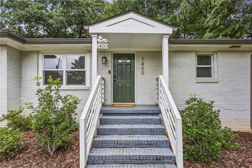 Welcome to 1400 Smith Street SE, an impeccably renovated three-bedroom, two-bath ranch nestled on over half an acre in the heart of East Atlanta. Set on a rare, flat, oversized lot that feels like a private park oasis, this home offers an incredible combination of style, comfort, and privacy, just minutes from East Atlanta Village, the BeltLine, and local favorites. Step inside to discover refinished hardwood floors, fresh paint, an open-concept layout, and a light-filled kitchen with stainless steel appliances, a gas stove, venthood, tile backsplash, and views into the dining and living areas, perfect for everyday living and entertaining. The primary suite is a true retreat with its own private entrance to the back deck, a spa-like bath featuring a walk-in shower, dual vanities, and a custom built-in walk-in closet. Two secondary bedrooms share a beautifully updated full bath. A dedicated office with custom iron doors and a dry bar offers an ideal work-from-home setup, flex space, bar room or playroom. Enjoy outdoor living on the spacious screened-in porch, a large patio with bistro lights, and a large back deck overlooking the fully fenced and landscaped backyard, a rare find in the city. There is plenty of storage space in the unfinished exterior entry basement that is approx. 17’ by 21’ ! Additional highlights include a laundry room off kitchen with sink and shelving, keypad entry, Ring doorbell and cameras, and a shed for extra storage. Major system upgrades include a newer roof, replaced HVAC and ductwork (with zone damper), professional basement waterproofing with lifetime warranty, updated plumbing, fencing under the deck, and updated light fixtures throughout!