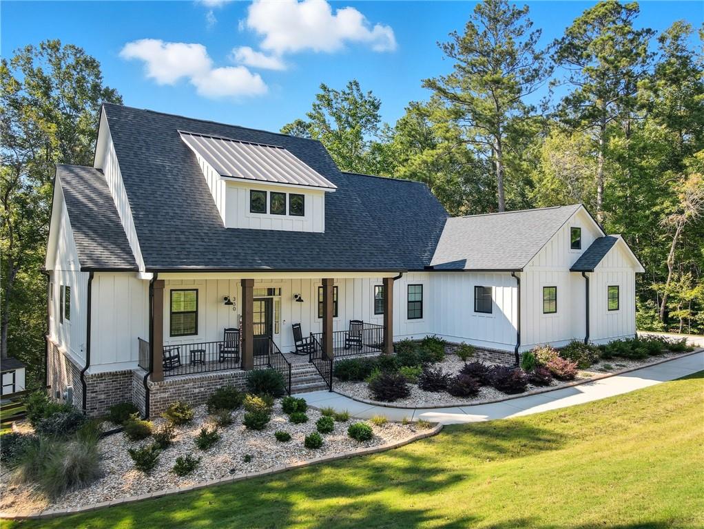 This stunning modern farmhouse is better than new, thoughtfully upgraded, and perfectly set on over 2 acres in the exclusive gated Tate Reserve community of Ball Ground. From the moment you step inside, soaring 10-foot ceilings, 8-foot doors, and expansive windows create a bright, open feel that highlights the home’s custom details. The spacious great room, anchored by a striking fireplace, flows effortlessly into the chef’s kitchen—complete with 42-inch soft-close cabinetry, gleaming granite countertops, stainless steel appliances, a 5-burner gas cooktop, upgraded hood vent, and a generous island designed for gathering. The main-level owner’s suite is a private retreat, featuring a spa-like bath with a frameless walk-in shower, soaking tub, double vanity with granite counters, and an oversized walk-in closet. Two secondary bedrooms on the main level share a full bath, while the finished terrace level presents the perfect in-law suite setup. This expansive area includes a spacious living room, a kitchenette with an eat-in island, an open dining area, a full bath with a tiled walk-in shower, and two additional bedrooms—one of which is currently used as an office. Outdoor living shines with a covered back porch overlooking the grassed and fenced backyard and a lower-level patio that’s perfect for entertaining or quiet evenings surrounded by nature. A side entry 2 garage, mudroom with drop zone, and professional landscaping complete this extraordinary home. Blending modern design, functionality, and timeless charm, this home offers the very best of North Georgia living in a secure, gated setting—just minutes from downtown Ball Ground, Canton, and GA-575.