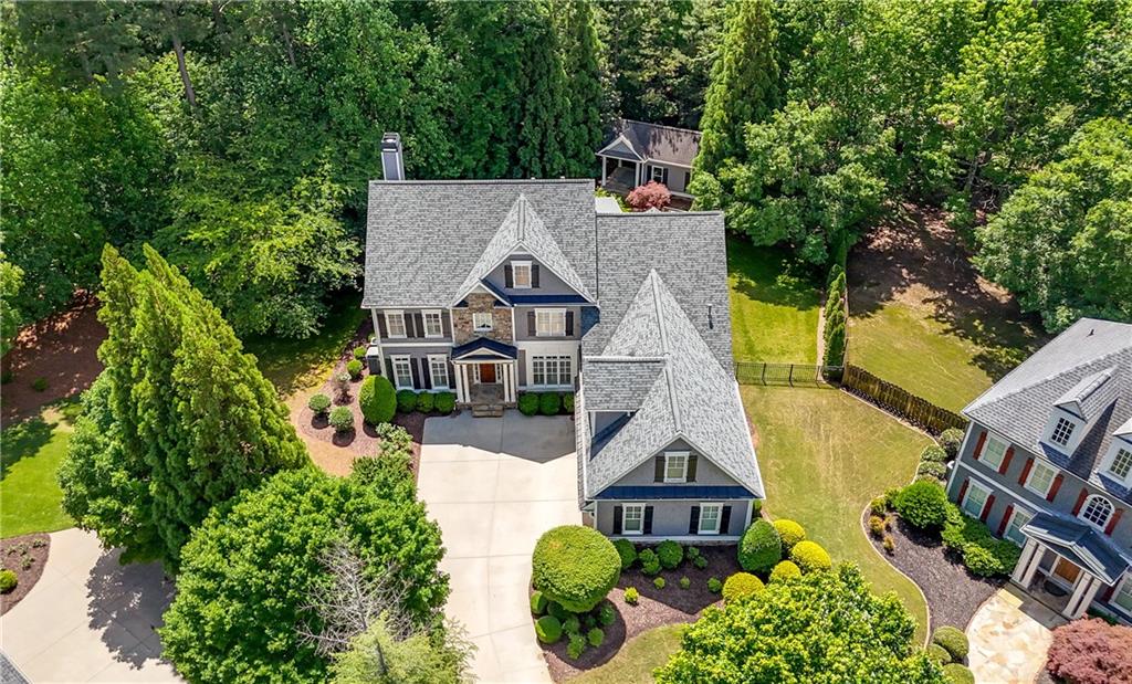 Welcome to your dream home nestled in the sought-after Park at Kirk Farms, perfectly situated on a quiet cul-de-sac just minutes from Mount Paran Christian School, Marietta Country Club, Marietta Square, and Kennesaw Mountain. This meticulously maintained residence offers timeless elegance with wood floors throughout the main level and a warm fireside family room showcasing a dramatic floor-to-ceiling stone fireplace. The chef’s kitchen is a showstopper, featuring Jenn-Air appliances, a gas cooktop with vent hood, double wall ovens, a GE Adorn side-by-side fridge/freezer, two pantries, and a custom-built-in desk area with wet bar plumbing already in place. The stunning owner’s suite offers a spa-like bathroom and a spacious walk-in closet with custom organizers. Throughout the home, you'll find Levolor blinds and plantation shutters, a beautifully appointed laundry room with sink and cabinetry, and a spacious three-car garage complete with built-in wall storage. Step outside to a serene, fully fenced, flat backyard with landscape lighting, irrigation, a playset, room for a pool, and a lovely back deck perfect for entertaining. The property extends beyond the fence and includes a detached 200-square-foot A-frame garden studio with a covered porch, wood floors, 14-foot ceilings, wainscot paneling, split-zone AC, R-60 insulation, a bottle fridge, flat panel LCD TV, surround sound, and a hidden floor safe—ideal as a she-shed, man cave, art studio or private office. Recent upgrades include a full roof replacement in 2020, new main level HVAC in 2022, attic re-insulated to R-60 in 2016, a new water heater in 2019, and a complete replacement of the main water line from the street in 2022. The home was freshly painted in 2022, and Lanier added custom cabinetry to the kitchen and library in 2016. With a blend of luxury, function, and prime location, this home truly has it all—come see it for yourself!