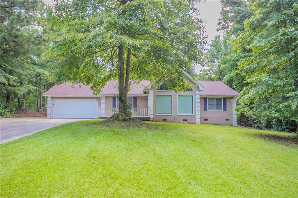 Single-story ranch in Countyline Acres offering flexible space and peaceful surroundings. This three-bedroom layout features a vaulted living room with a fireplace, an open-concept kitchen with solid surface counters and eat-in area, and a spacious laundry off the main level. The large lot offers privacy, wooded edges, and a rear deck for outdoor living. Bonus garage parking includes both an attached and detached garage—great for additional storage or workspace. No HOA or rental restrictions, just minutes from downtown Palmetto and easy access to I-85.