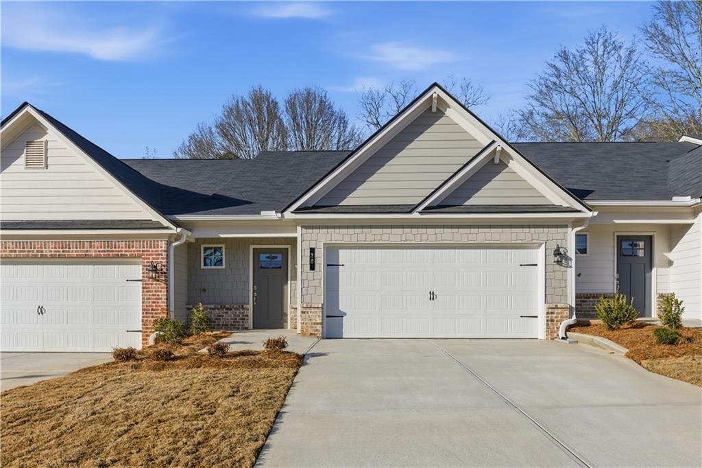 Exterior featuring a two-car garage, brick accents, board and batten siding, shake siding, and a dark front door with window inserts