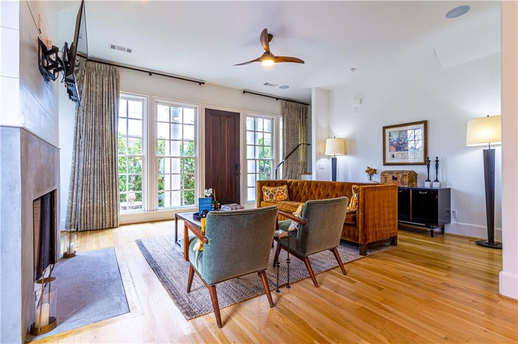 Living area with light wood-style flooring, ceiling fan, and a fireplace