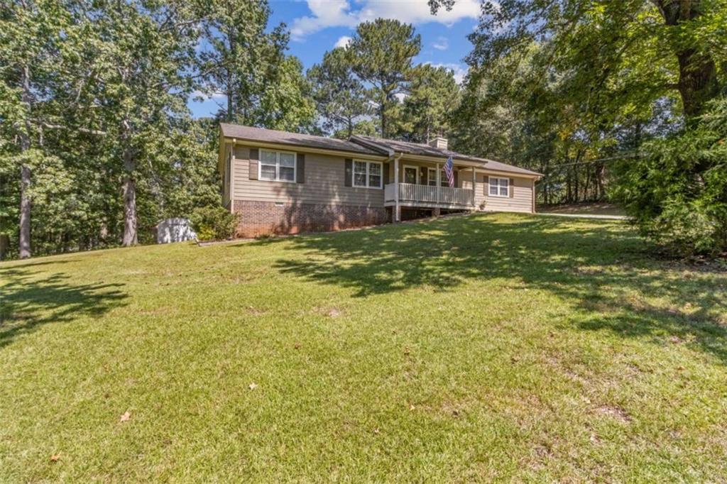 Charming and Spacious Ranch on Large Corner Lot in the Heart of Loganville! Welcome to this beautifully maintained level ranch-style home nestled on a generous 0.64-acre corner lot, offering both privacy and space in a highly desirable location. This well-maintained residence features an open, family-friendly floorplan designed for both comfortable living and effortless entertaining, with vaulted ceiling enhanced by beautiful wood beams. Step inside to find gleaming hardwood floors, newer paint, and newer carpet. The inviting living room boasts a beautiful stone fireplace and seamlessly flows into the open-concept dining area, creating the perfect gathering space. Just beyond, you'll find a cozy family room adjacent to the galley-style kitchen, complete with a newer dishwasher and a spacious laundry room nearby for added convenience. This home offers four generously sized bedrooms and two full bathrooms, including a converted garage that now serves as a private 4th bedroom or flex space, complete with a separate entrance-ideal for guests, a home office, or media room. The fenced backyard is your own private retreat, featuring a separate pet area, storage shed, and ample space for outdoor entertaining. Whether you're relaxing on the covered front porch or enjoying the large rear deck, you'll love spending time outdoors in this peaceful setting. Additional highlights include a clean, dry walk-in crawl space for extra storage, and a prime location just minutes from Loganville's shops, restaurants, parks, and major highways. With nearly 2,000 square feet of living space, this home offers the perfect canvas to make your own. Whether you're upsizing, downsizing, don't miss your opportunity to own this Home as you make it your own!