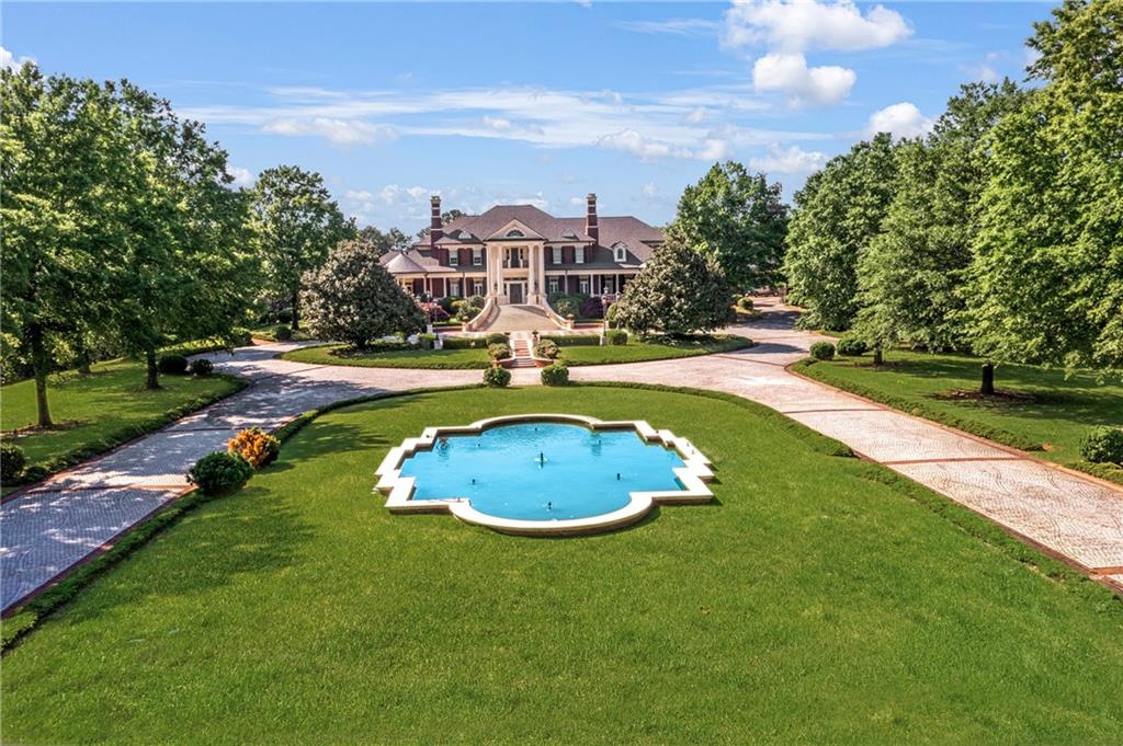 Introducing the most spectacular gated estate in Suwanee on over 14 acres with custom sophistication and style. This awe-inspiring property features expansive private grounds and endless options of entertainment and relaxation. You will enjoy 6 Full kitchens featuring Subzero and Viking appliances, combined with 2 kitchenettes. The main Kitchen features a large scullery and walk-in pantry with a remote-controlled pantry shelving system. There is a second full kitchen just steps away with access to the covered porch and outdoor kitchen. The primary suite on the main levels is the perfect retreat with a covered balcony, large fireplace, his and hers bathrooms and his and hers custom closets. Upstairs you will enjoy more entertainment spaces, a kitchen, private rooms all featuring ensuites and custom closets. In addition to a walkup attic with custom cabinetry throughout. The elevator can be used to access the 3-floors. The terrace level features a true theatre, large game room, full kitchen, fireplace, multiple French doors to the walkout pool area, large bedroom, sitting room and full bath with steam shower and barber area. The enormous, heated saltwater pool can be enjoyed all year around with a retractable cover. The large outdoor stone fireplace is a perfect place to relax and walk over to grab a game of basketball on the court. The pool house features a large area that is currently a gym with another kitchen and bath. The extensive gardens are just behind the pool house. The garage is equipped for over 10-cars with custom flooring, cabinetry and HVAC. Your guests can enjoy ultimate privacy in one of the multiple apartments. The estate's luxe interior is matched by its manicured exterior, with professionally landscaped gardens that bloom in vibrant colors throughout the seasons. The lush greenery leads you to the private lake, where you can enjoy serene moments fishing from the dock or a leisurely ride on a paddleboat. Two gated entrances provide convenience and security, making this property ideal for entertaining and valet parking for your guests. This extraordinary property is more than a home; it is a sanctuary designed for those who seek the ultimate in luxury living. With every imaginable amenity and an unparalleled level of craftsmanship, this estate is truly a masterpiece that must be experienced to be believed.